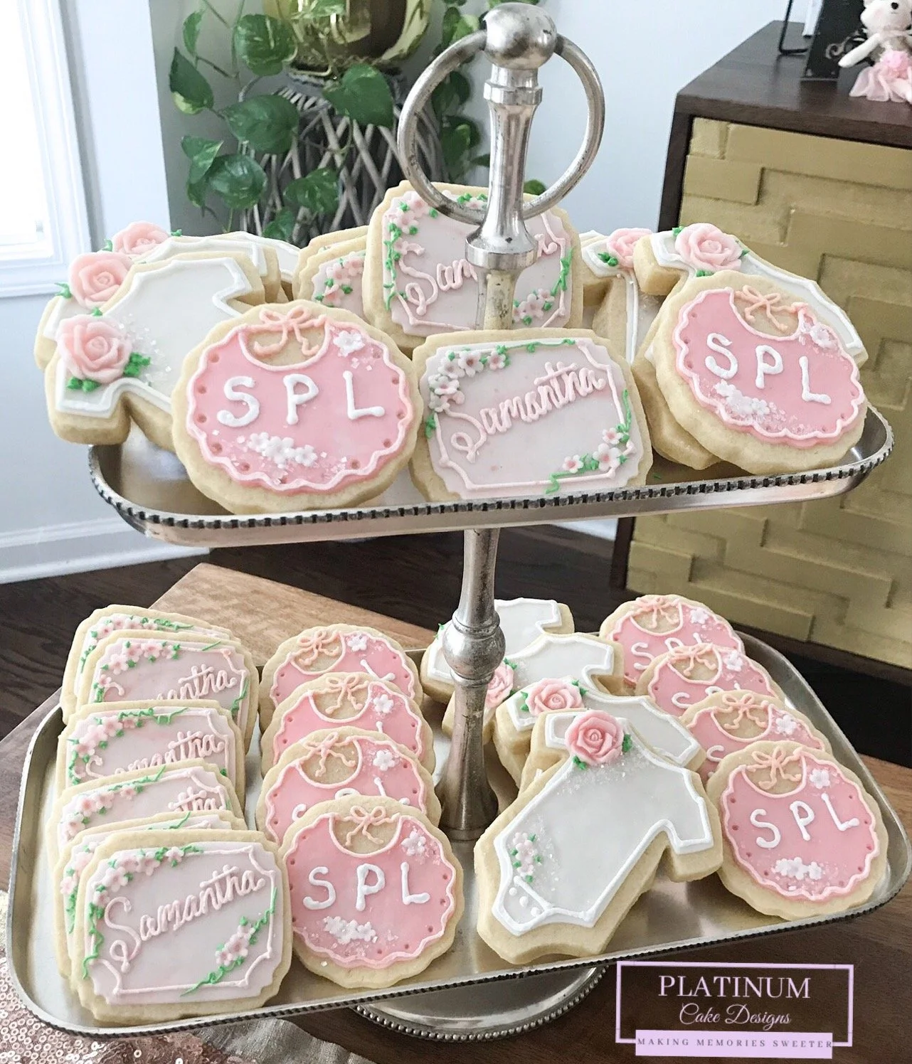 Platinum Cake Designs created these delicate custom cookies for a baby shower.  We customized these sugar cookies by adding the baby's initials on the bib and the throughline was the baby pink color and flowers.