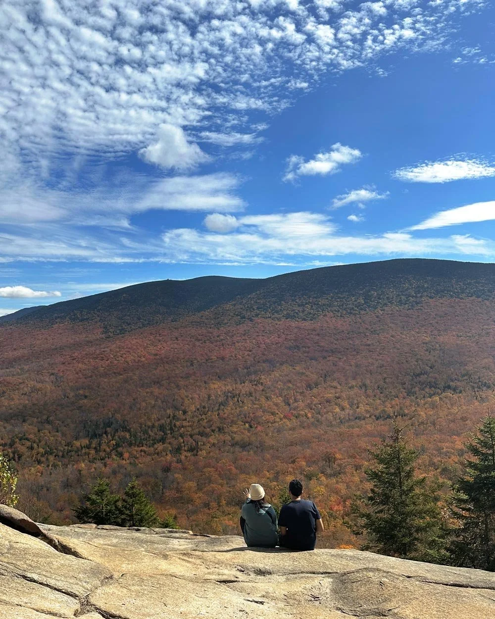 Couple assis sur un rocher devant une montagne en automne