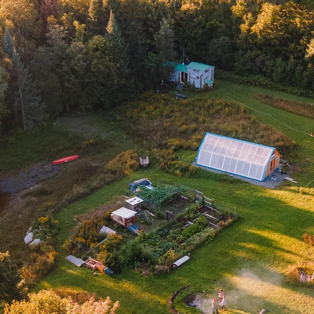 Vue aérienne du site Aux Cinq Sens montrant les jardins, la serre solaire et l’espace feu, reflet d’un lieu déployé en cohérence