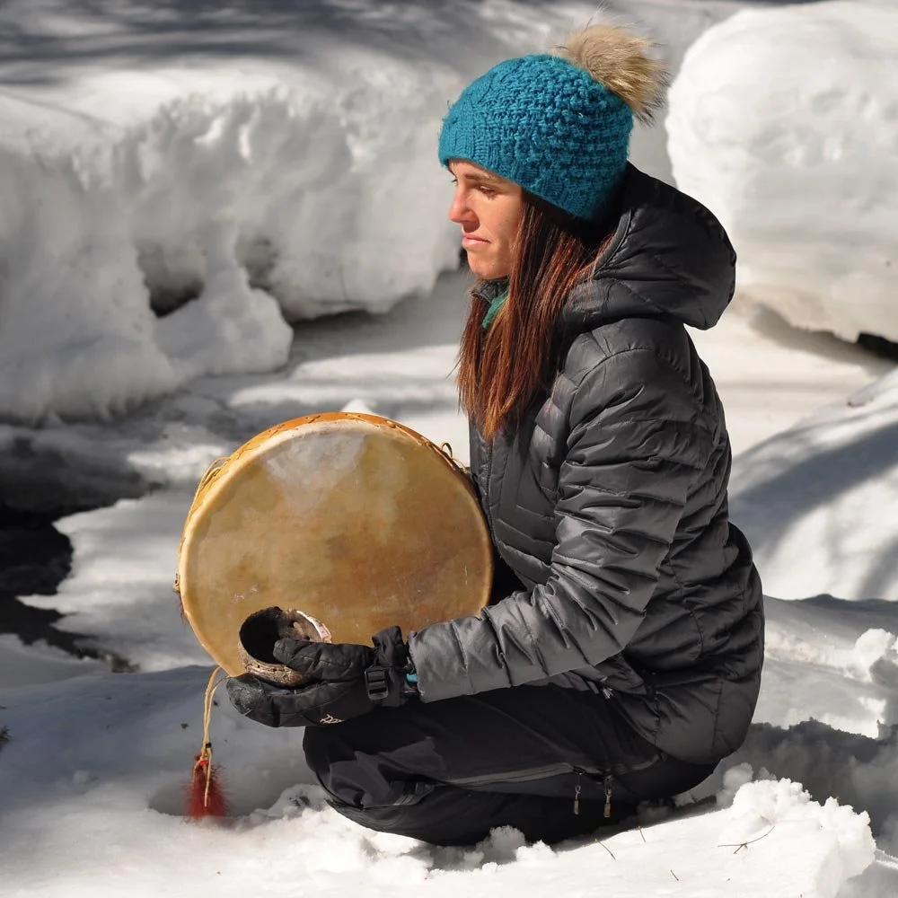 Paule au bord du ruisseau l'hiver avec son tambour dans un état d'intériorité.