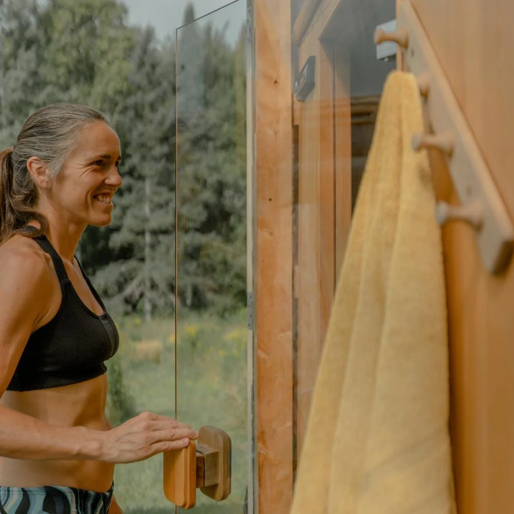 Femme entrant dans un sauna avec en arrière plan une forêt en été