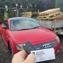 Person holding access card in front of red Audi car parked outdoors