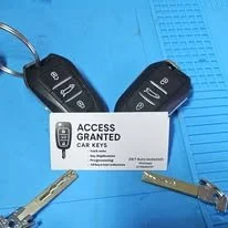 Two car keys and a white card with a key icon that reads 'ACCESS GRANTED CAR KEYS' on a blue background.