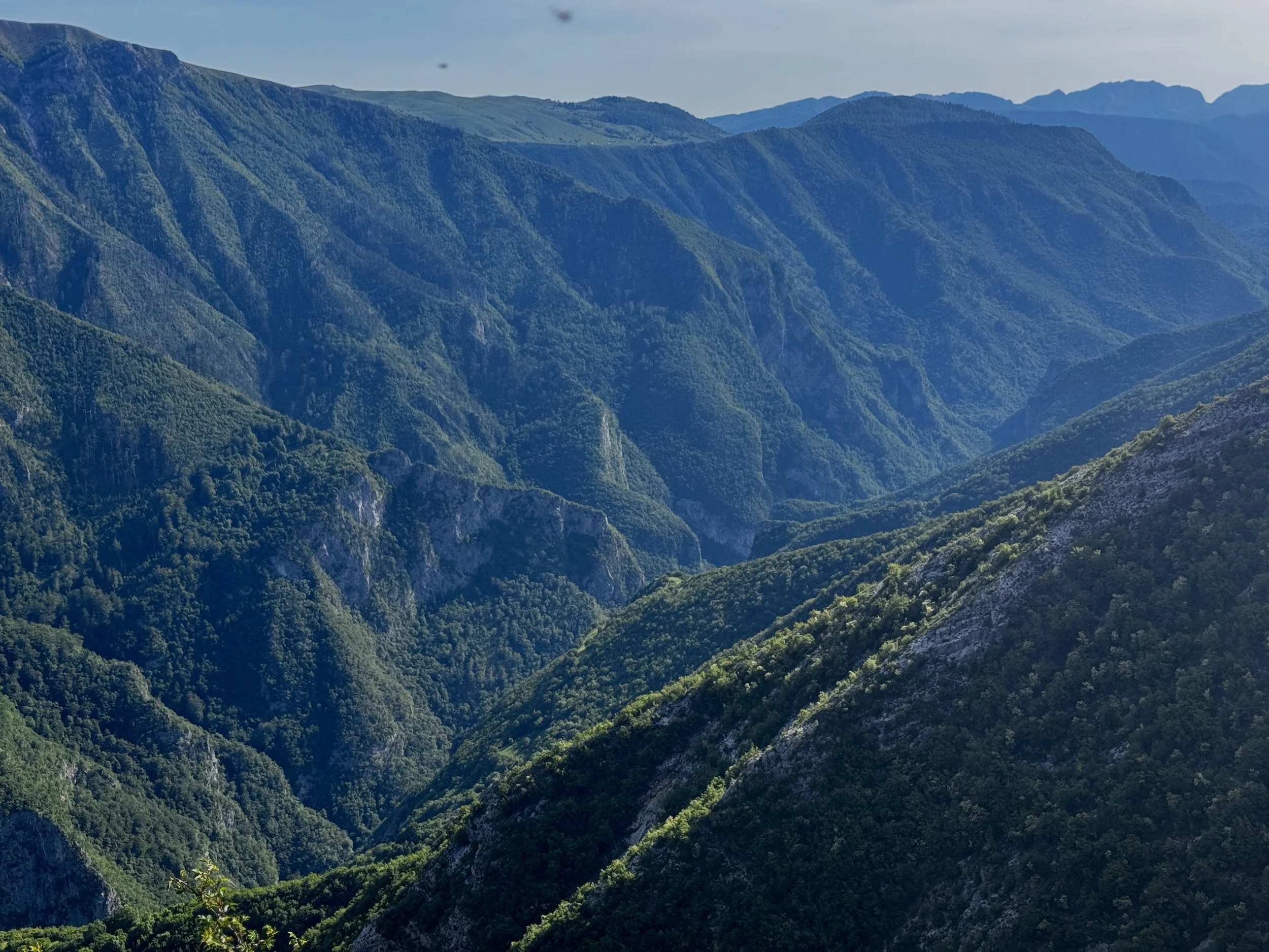 View of green, forested mountains under a partly cloudy sky.