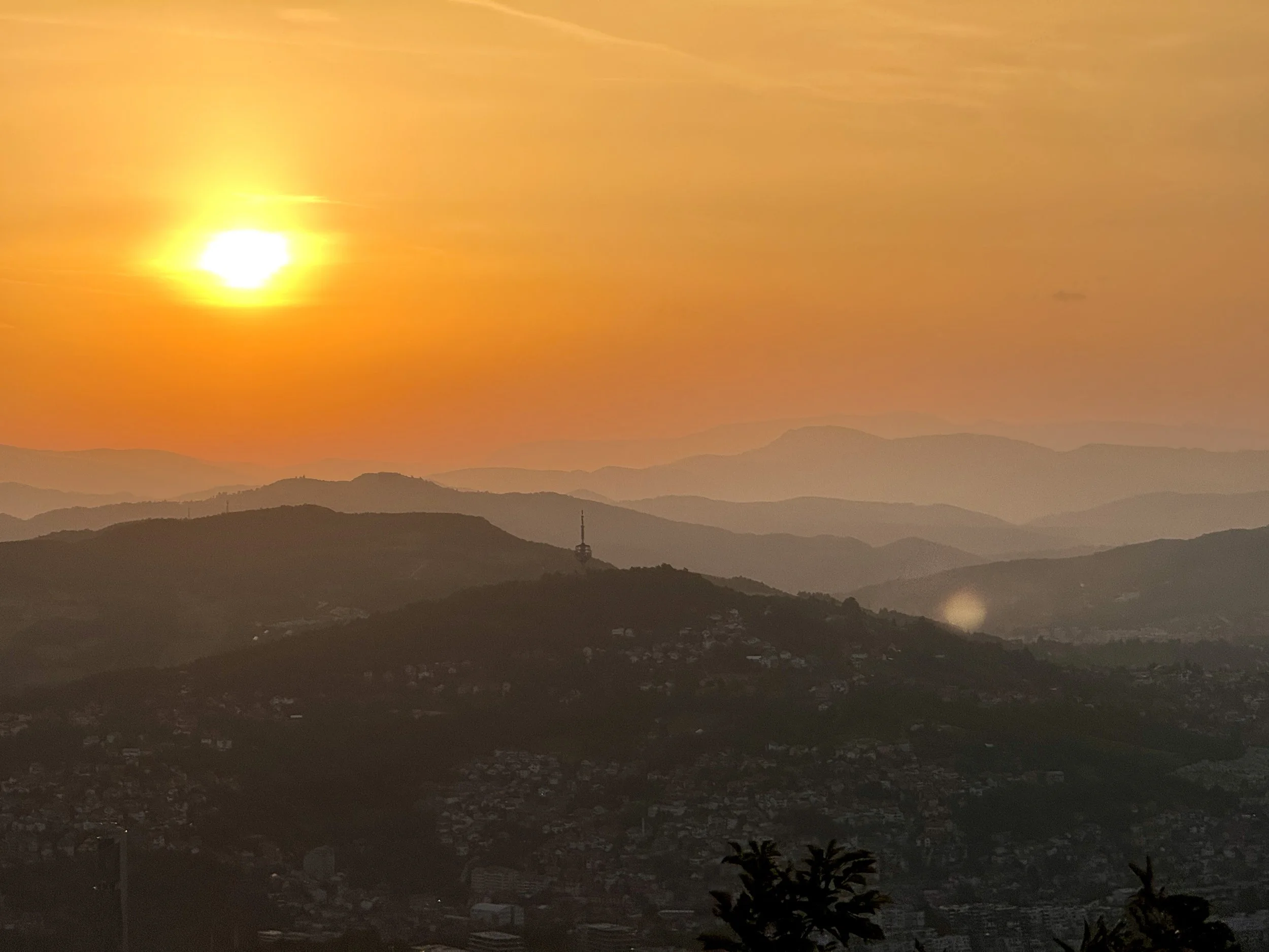 Sunset over misty rolling hills with a communications tower on a hilltop