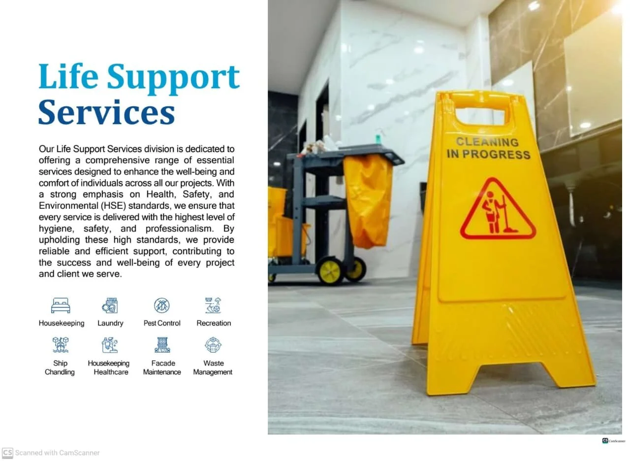 Information board about Life Support Services with icons for housekeeping, laundry, pest control, recreation, ship chandling, healthcare, facade maintenance, and waste management, positioned next to a yellow 'Cleaning in Progress' sign in a building corridor.