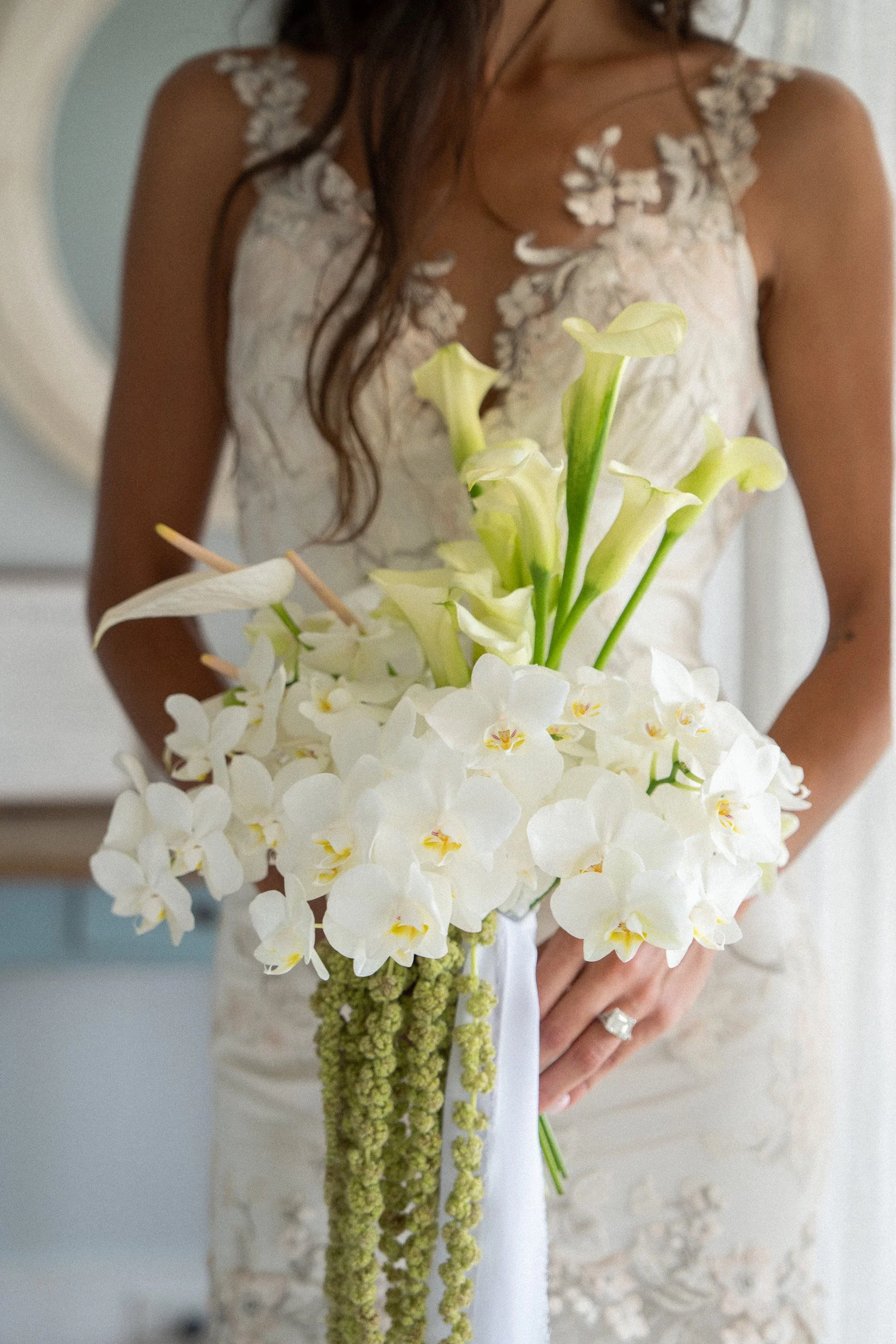 Woman in a wedding dress holding a bouquet of white and green flowers.