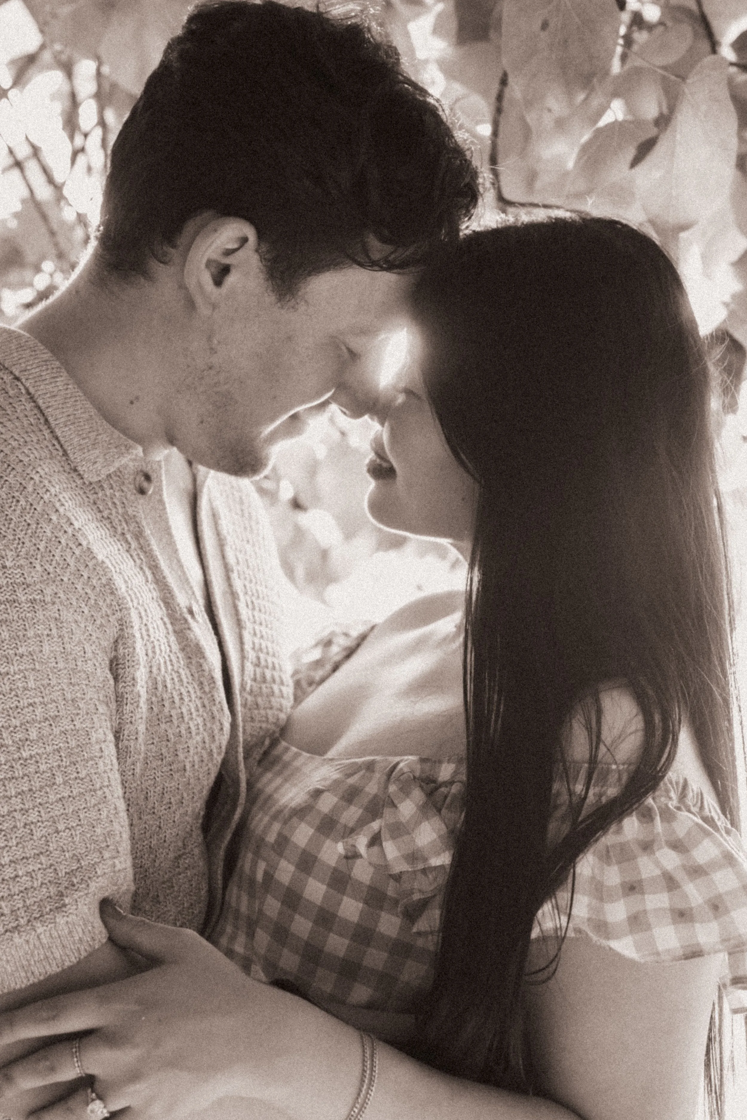 A black and white photo of a man and a woman close together, with their foreheads touching and eyes closed, sharing an intimate moment.