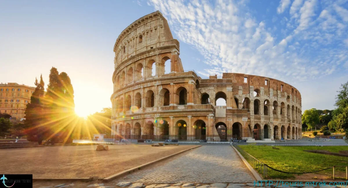 The Colosseum, an ancient Roman amphitheater, is shown at sunset with a partly cloudy sky.