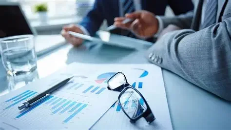 Business meeting with documents, pen, glasses, and a glass of water on a table.