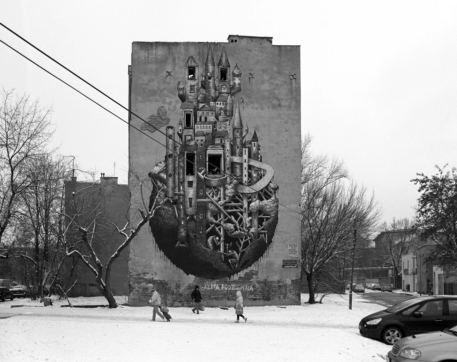 A large mural of a floating island with a fairy tale castle on top painted on the side of a building in a snowy urban scene, with people walking and parked cars in the foreground.