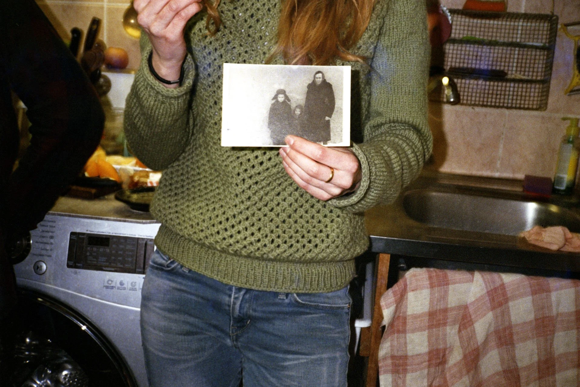 Person holding a black-and-white photograph of three people in a kitchen.