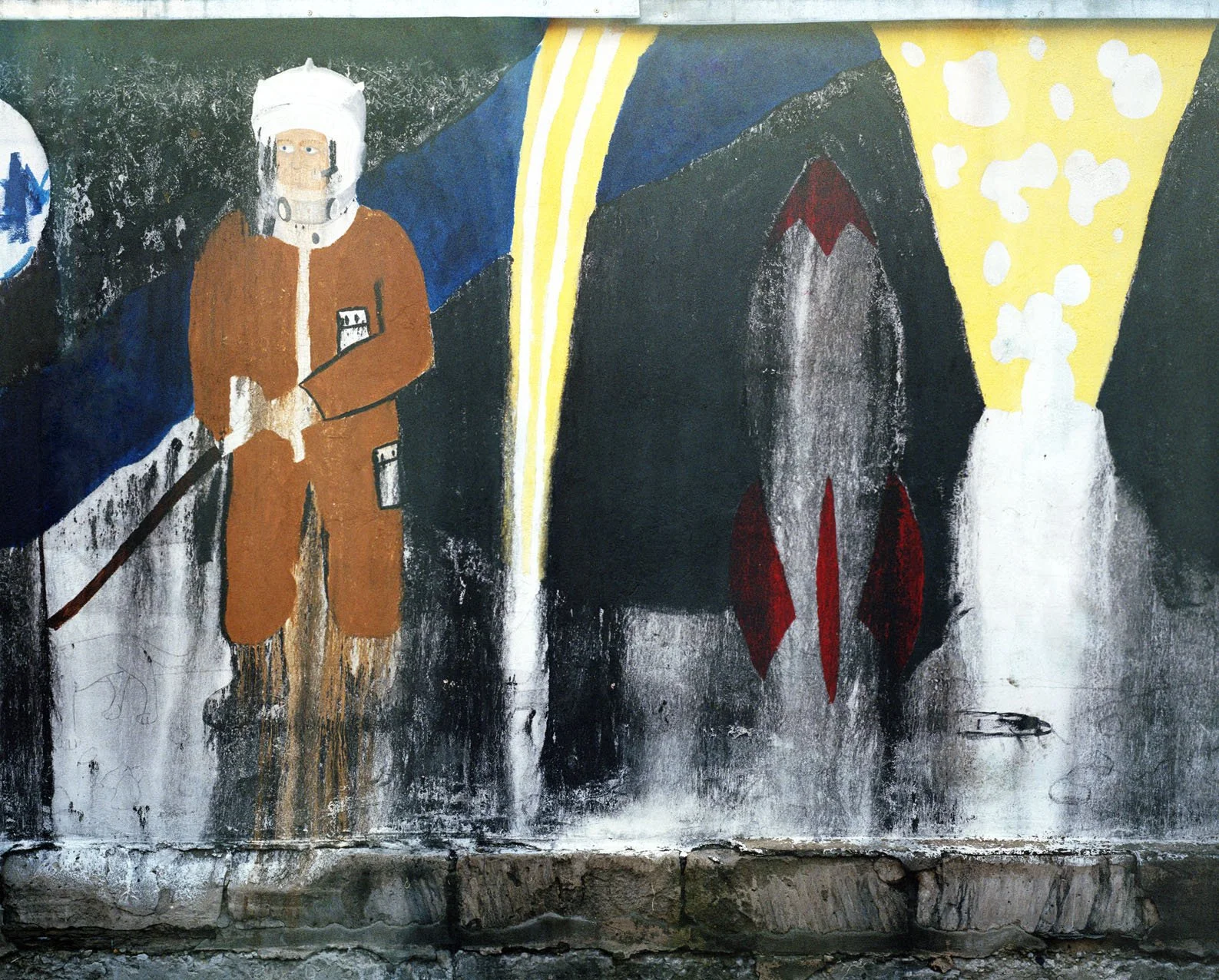 A mural showing a person in a space suit holding a tool, standing next to a rocket ship, with abstract shapes in the background.