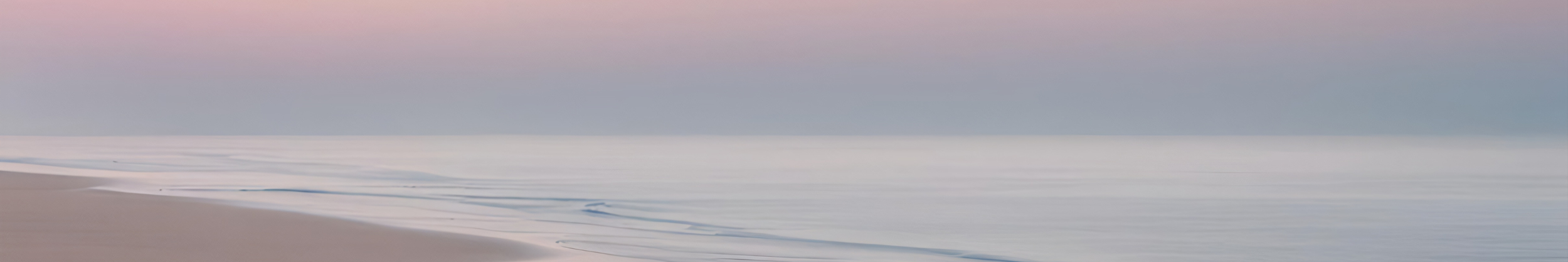 Beach with gentle waves and pastel-colored sky