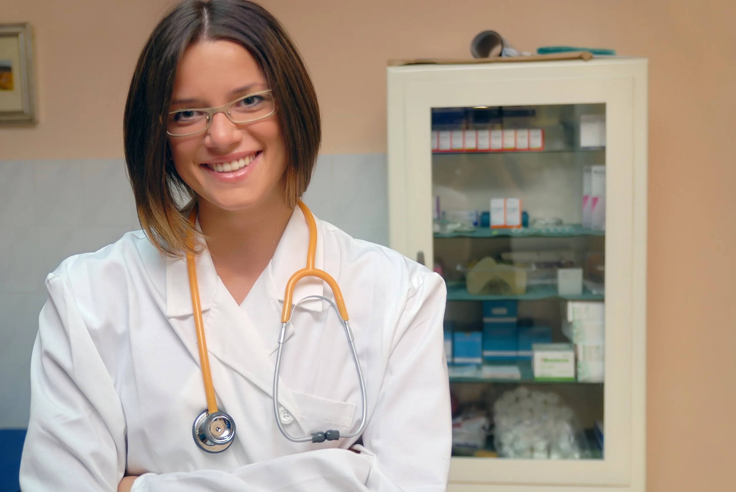 scottsdale auto injury clinic exam female doctor wearing glasses with a stethoscope around her neck in a business office setting smiling.