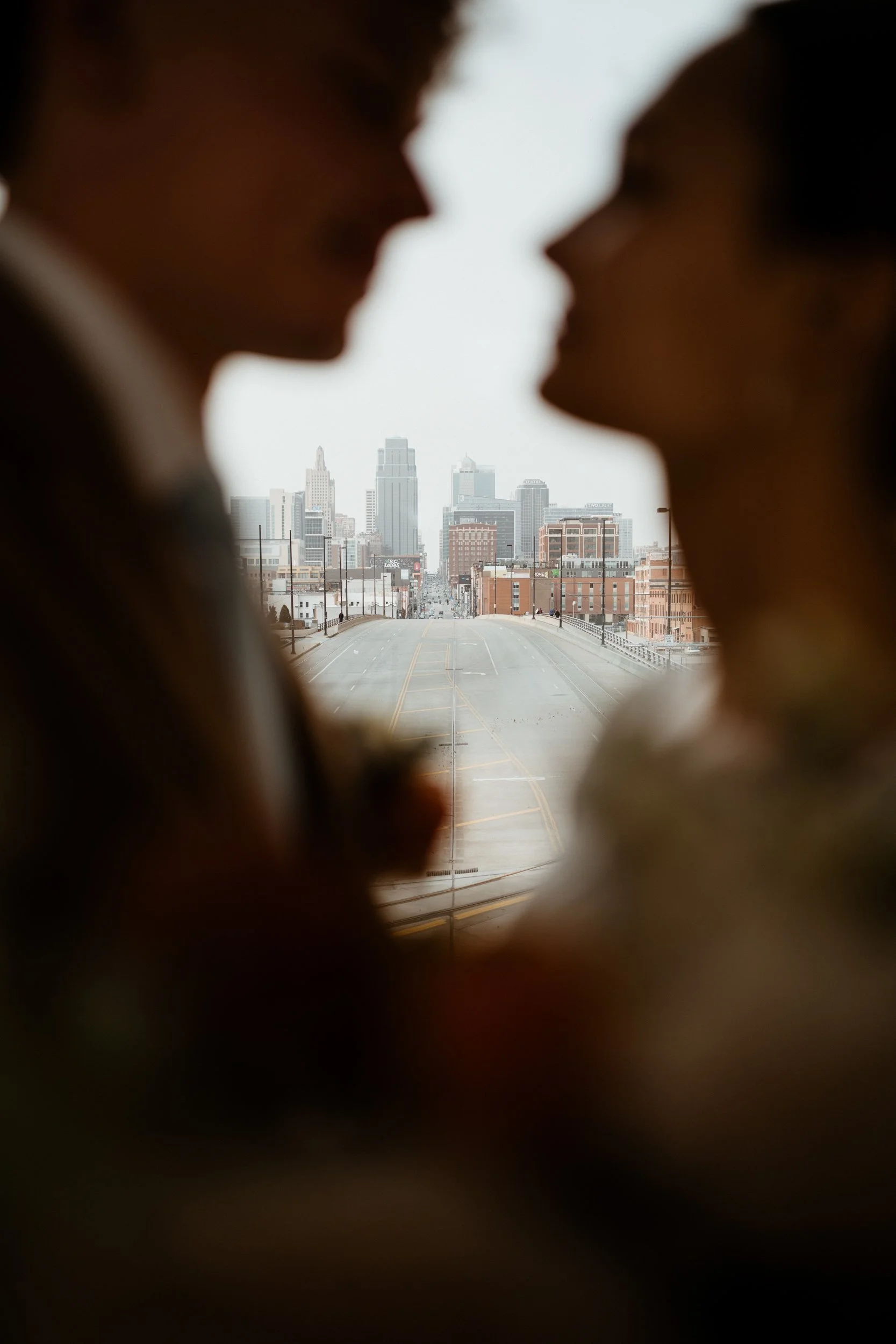 Silhouettes of a man and woman facing each other with a city skyline in the background.