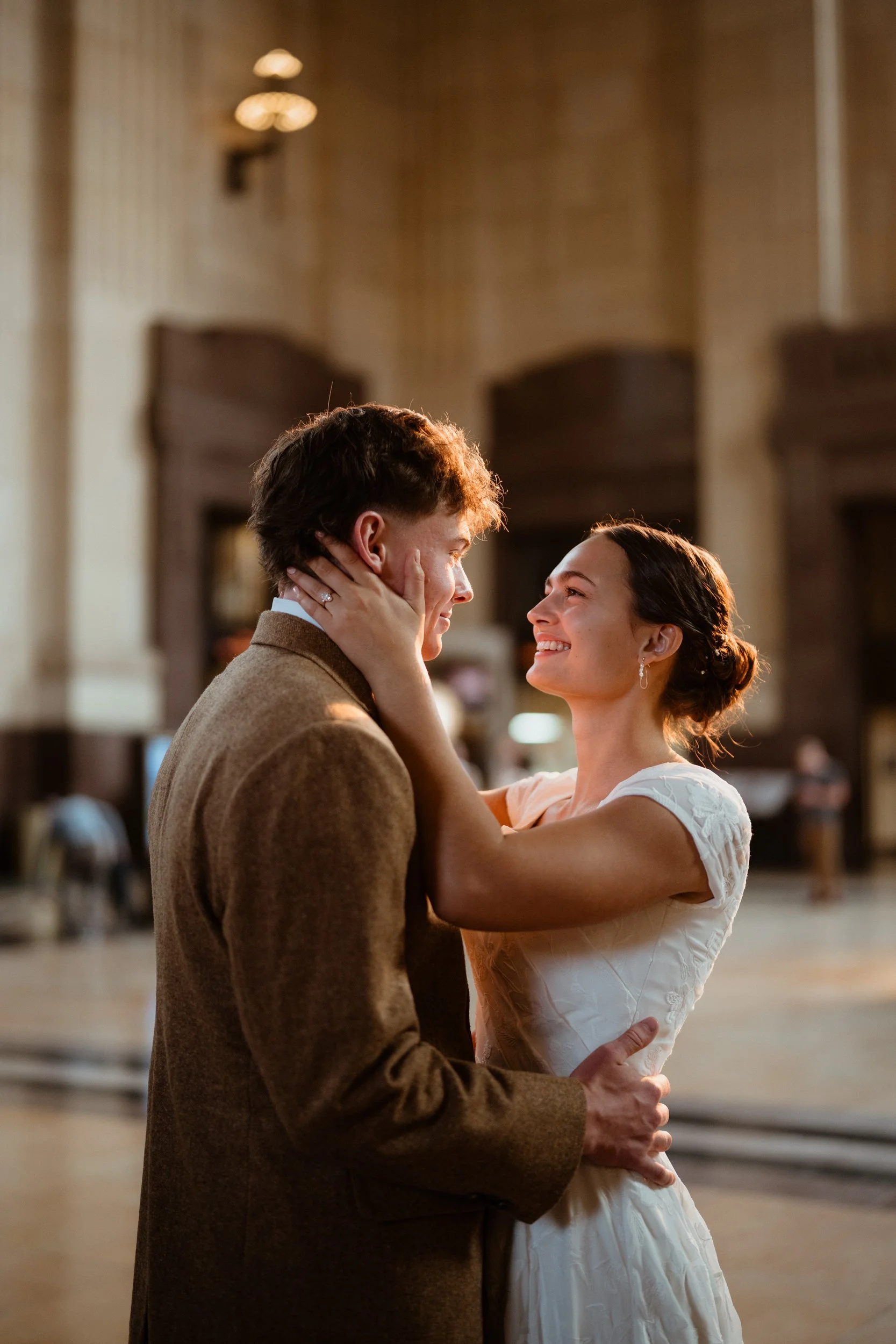 A couple dancing and smiling at each other in an elegant indoor setting.