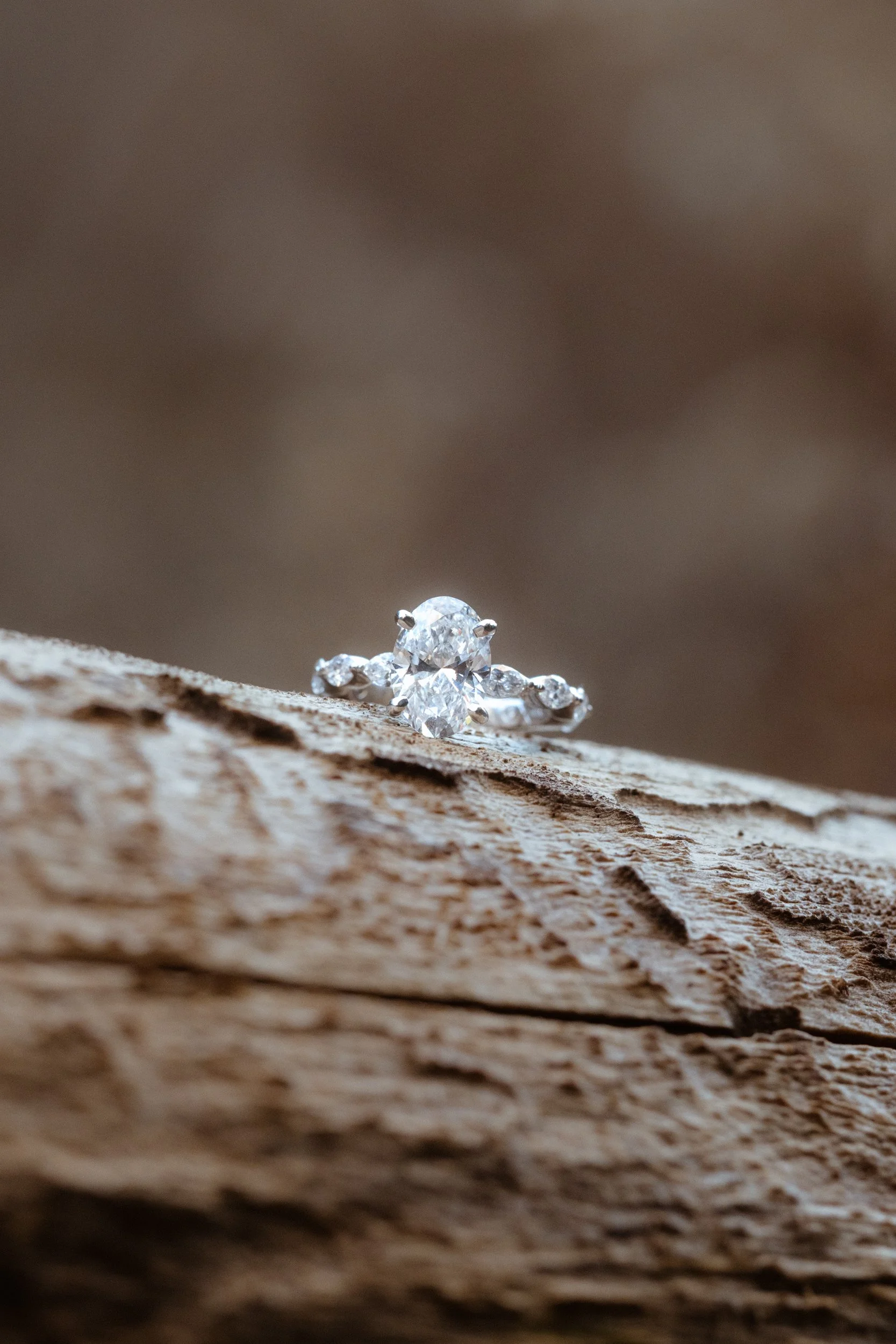 Close-up of a diamond ring with multiple stones resting on a textured piece of wood.
