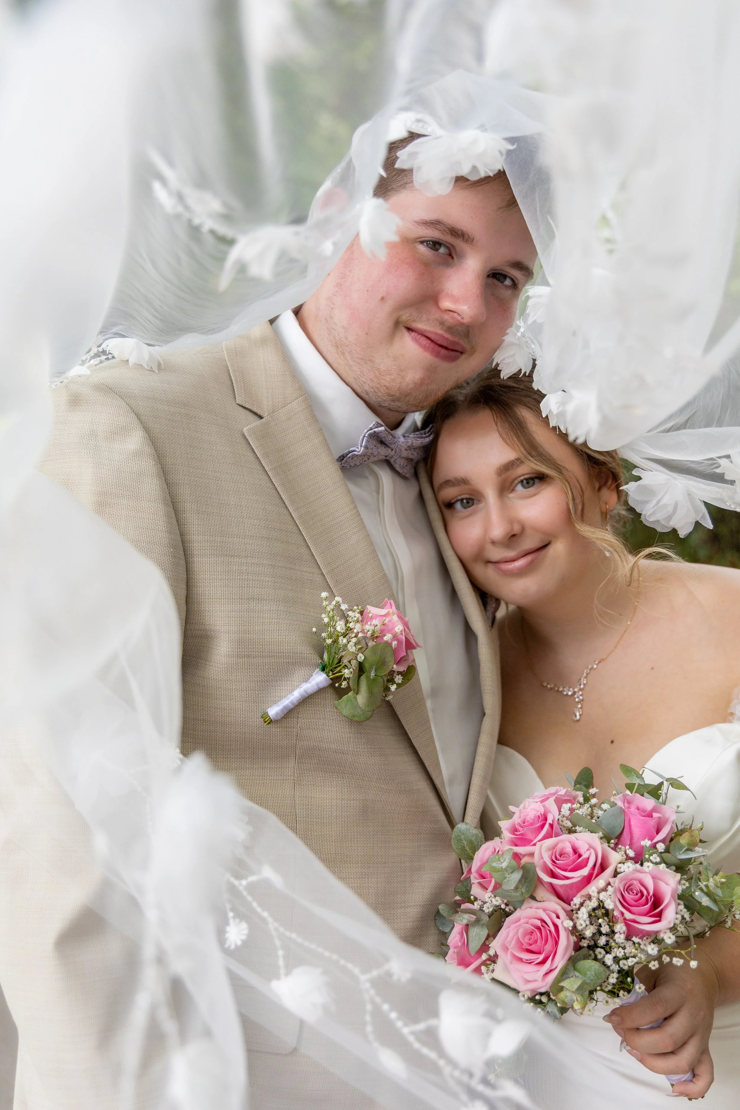 Ein glückliches Brautpaar aus Paderborn bei einer Hochzeit, umgeben von floraler Dekoration, die zusammen in einem festlichen Moment posieren.