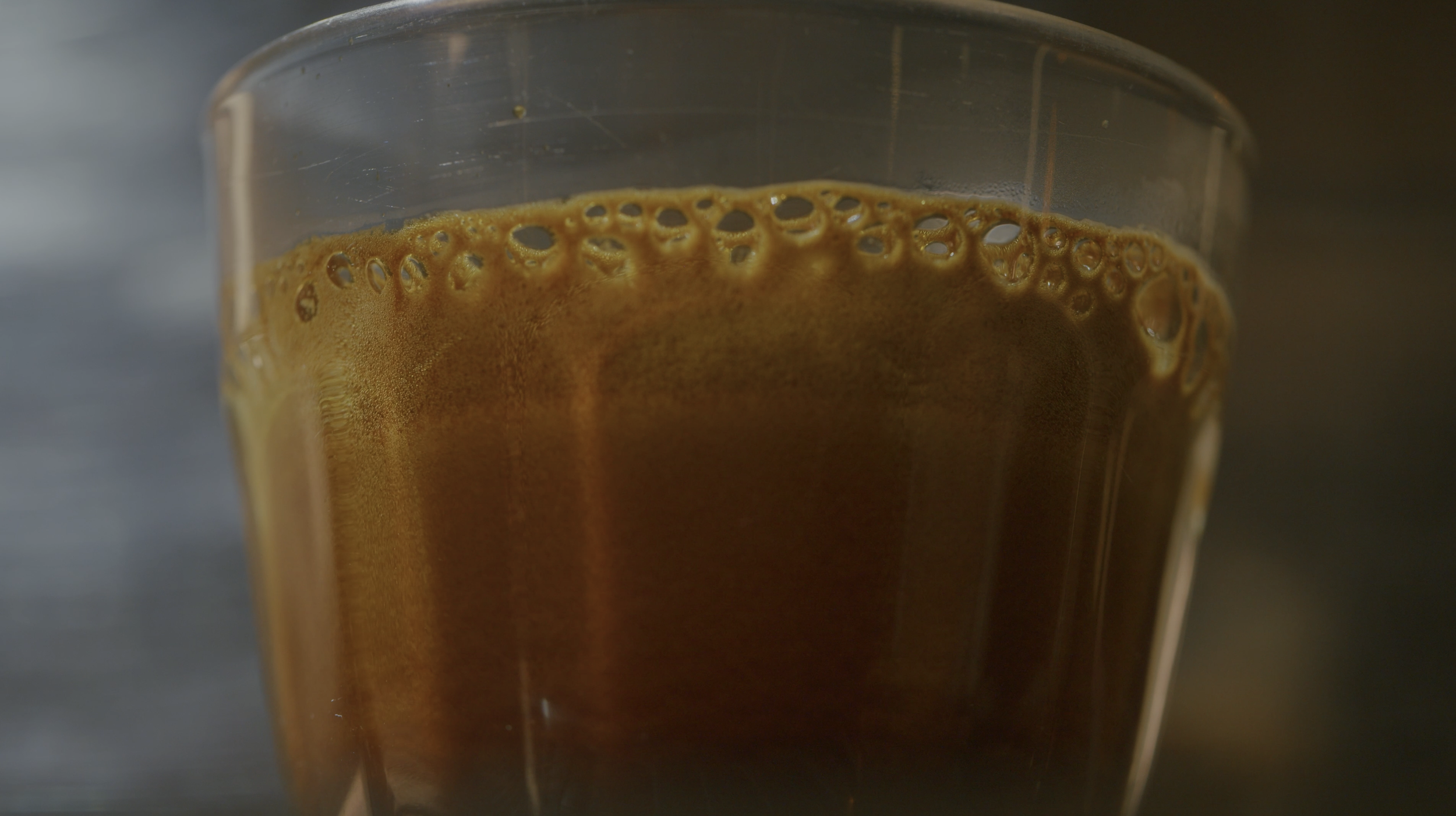 Close-up of a glass of freshly brewed espresso with visible bubbles on the surface.