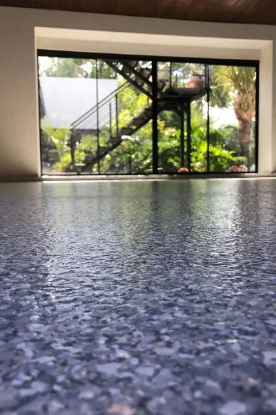 “Close-up detail of epoxy flake flooring showing gray, black, and white flake blend.”