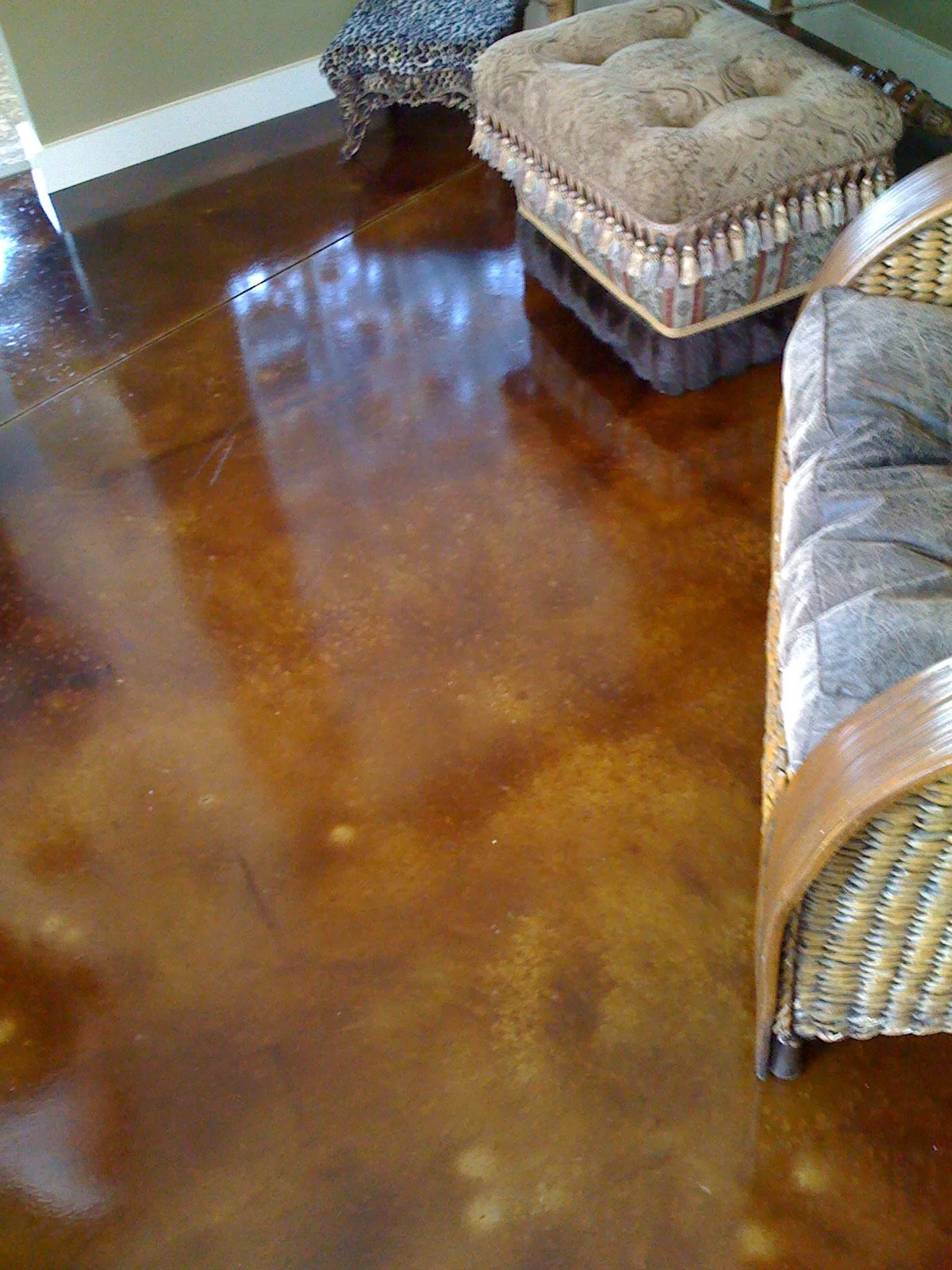 Polished hardwood floor in a living room with furniture including a couch with floral upholstery and a wicker chair.