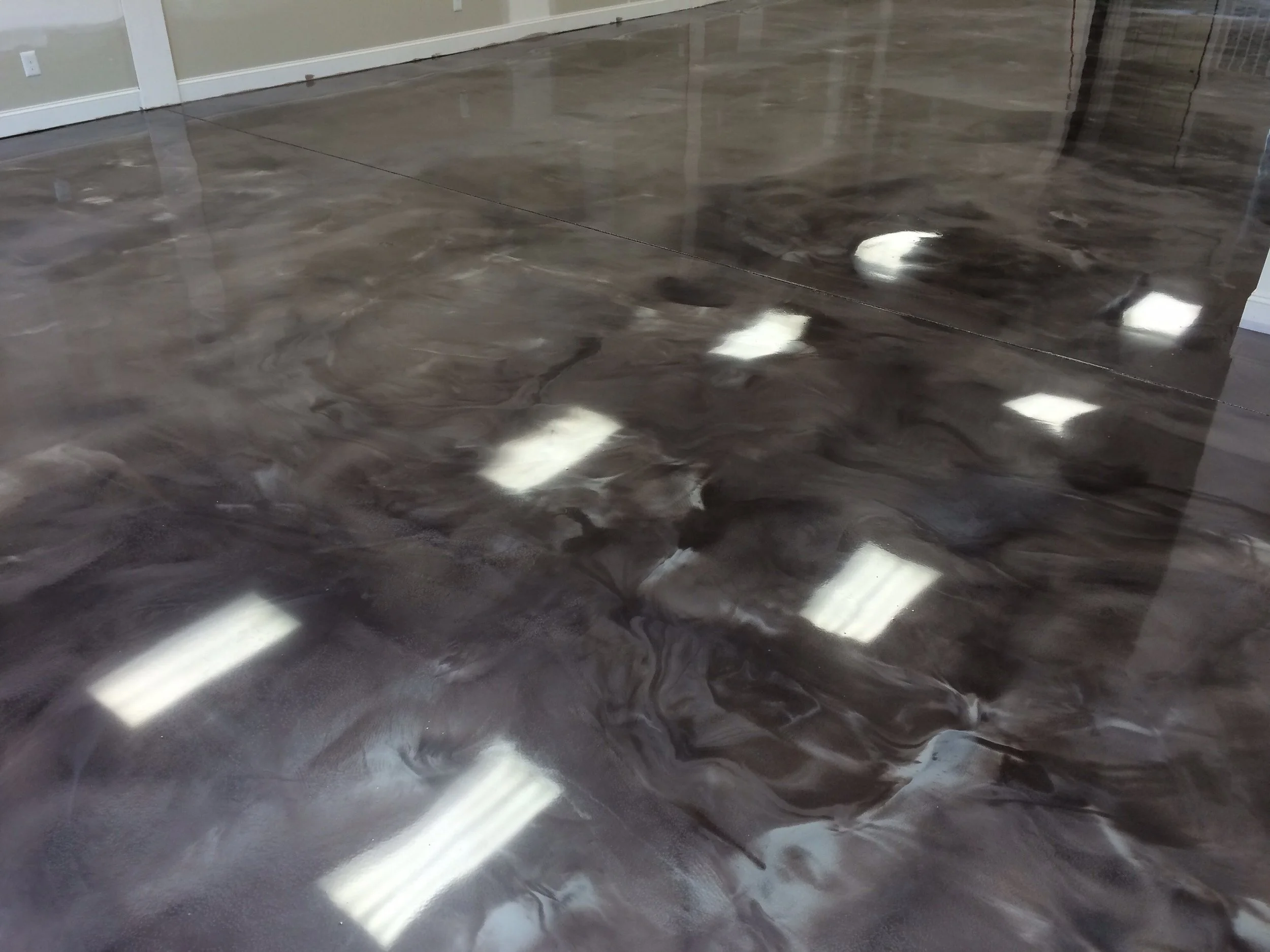 Polished dark marble floor with white reflections of ceiling lights.