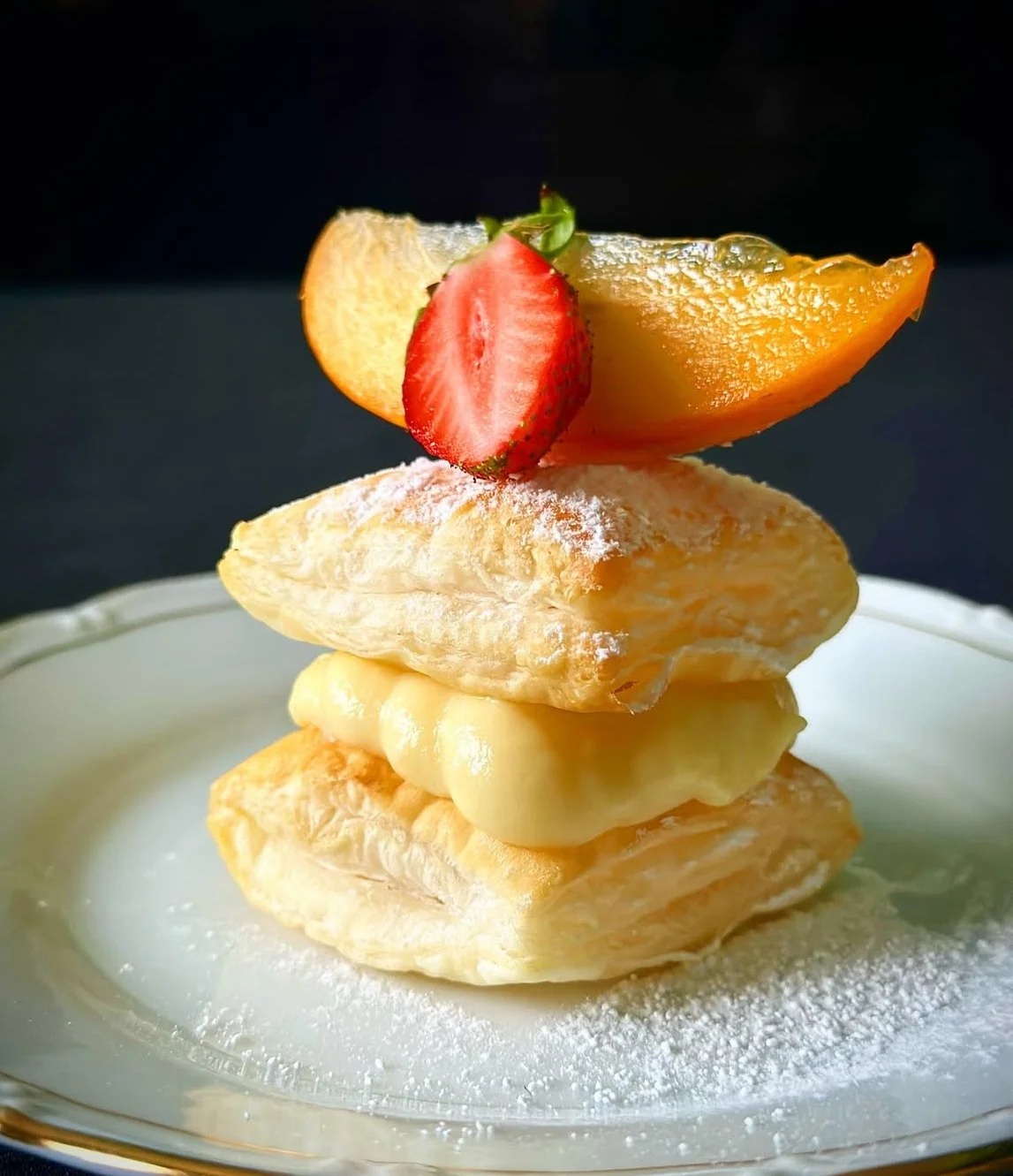 Torta di pasta sfoglia con crema e composta di fragole, decorata con melone, albicocca e fragola fresche.
