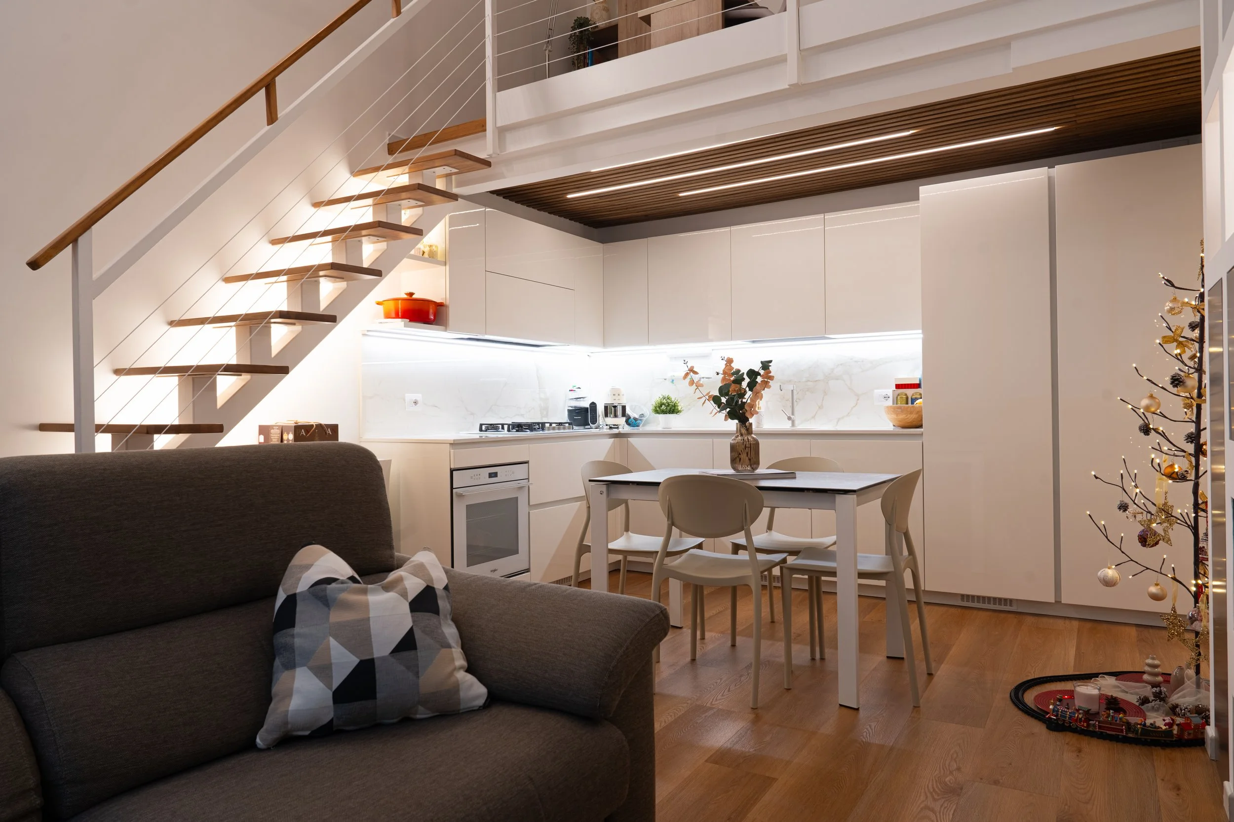 Interno di un open space con soggiorno e cucina, decorato per Natale con un albero decorato e un tavolo con fiori al centro.