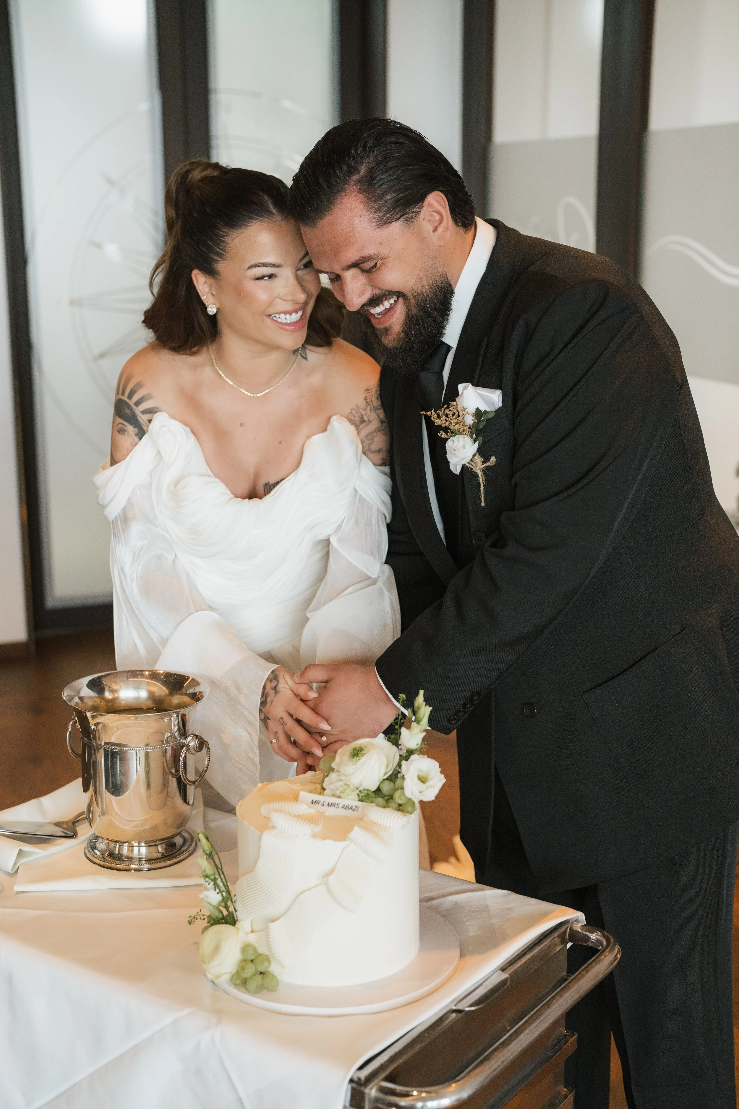 Ein Brautpaar teilt einen Kuss bei ihrer Hochzeit, während ein Zeuge im Hintergrund zuschaut.