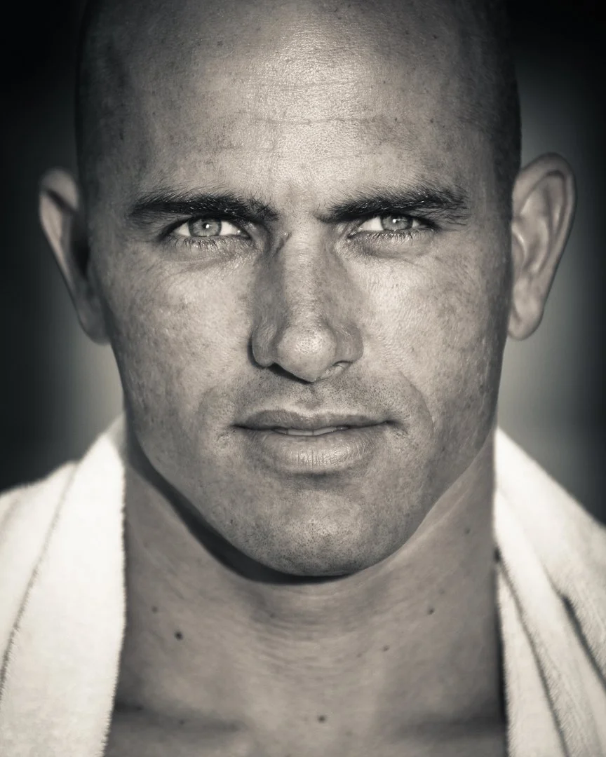 Close-up black and white portrait of a man with a shaved head, intense eyes, and slightly parted lips.