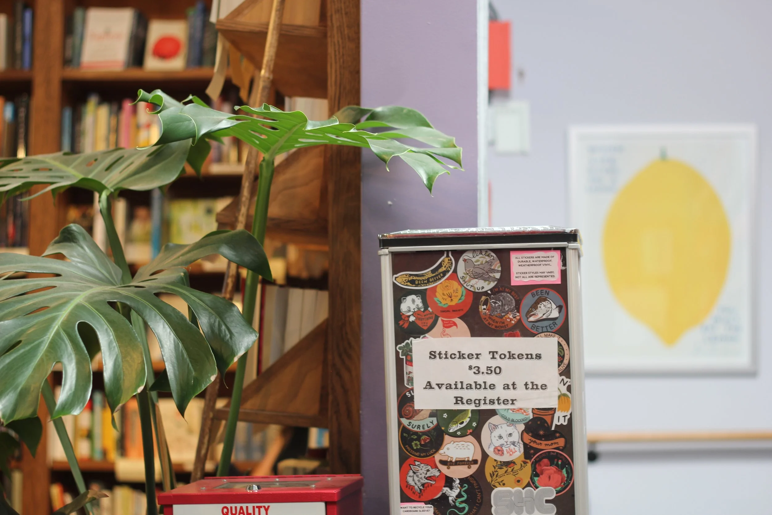 A collection of sticker tokens with various designs, available for $3.50 at the register, on display in a transparent container.