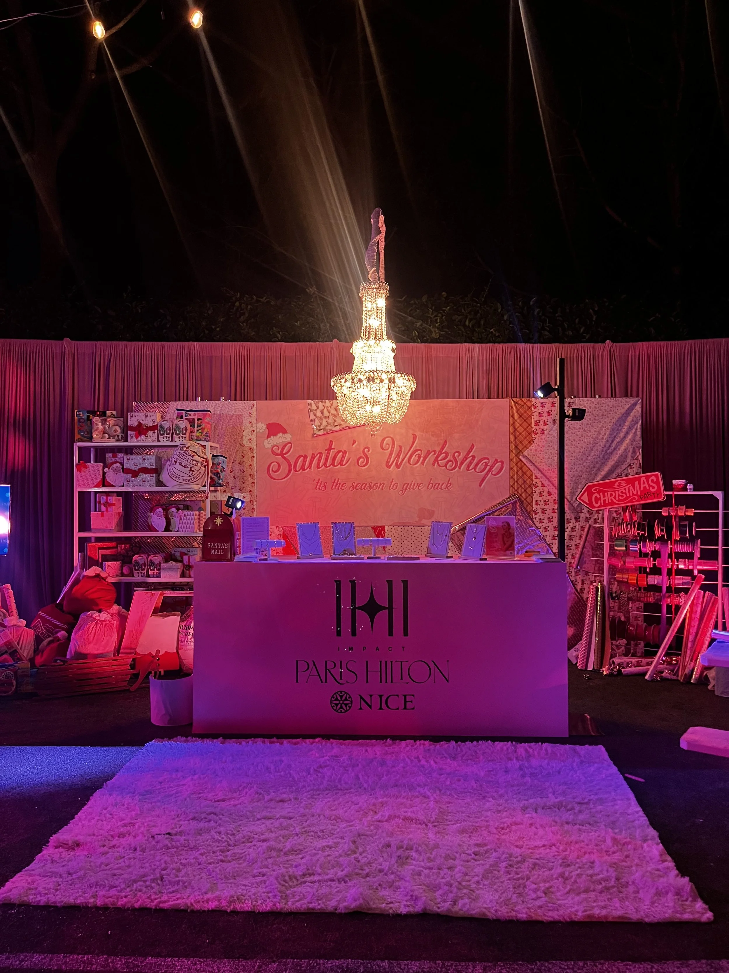 Christmas-themed display at Santa's Workshop with a pink and red color scheme, a chandelier hanging from the ceiling, and a pink fuzzy rug in the foreground.