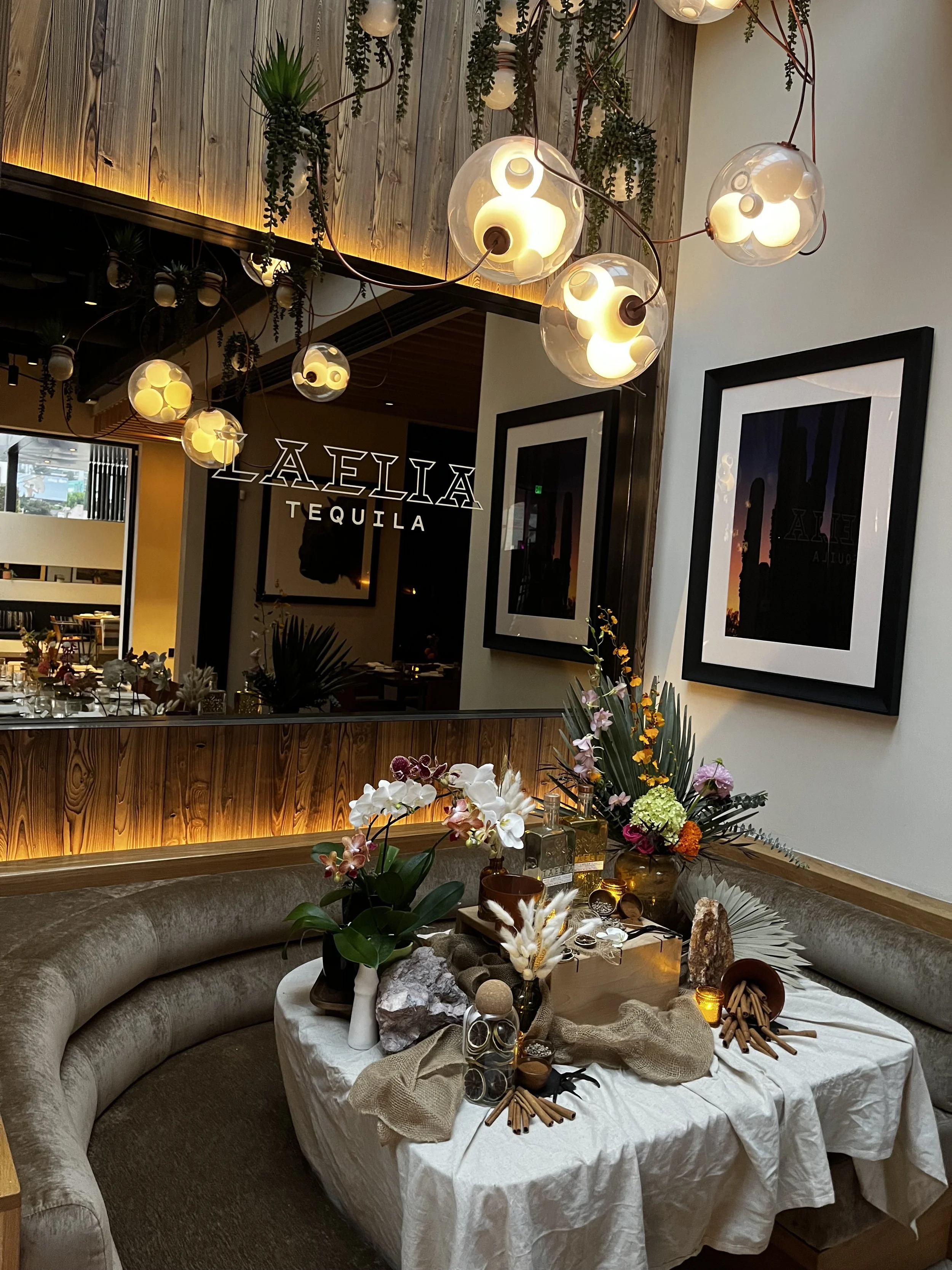Decorated indoor dining area at Laelia Tequila with floral arrangements, candles, and modern lighting fixtures.