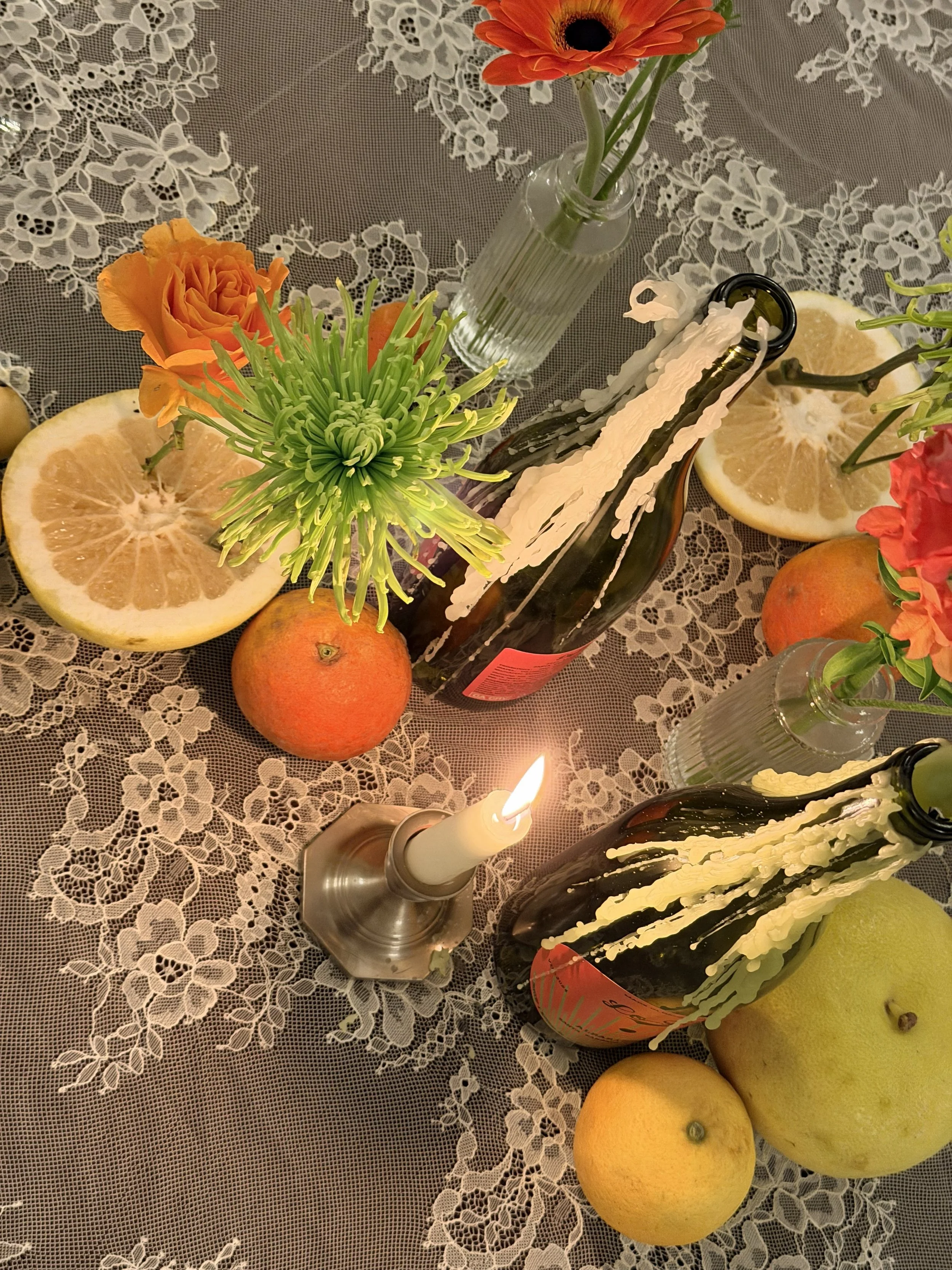 lofi tablescape at 1880 Union Hotel with vintage silver taper candle holders, wine bottle with dripping candles and fruit with artful posed flowers coming out of them