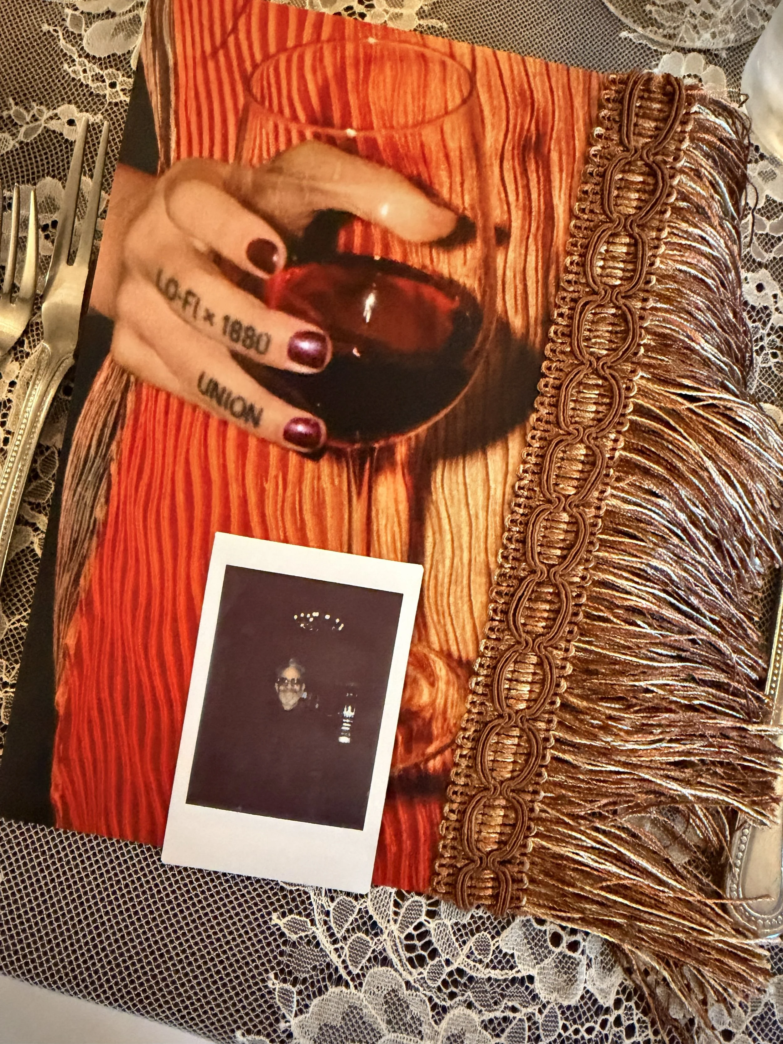 lofi menu with side fringe and picture of women holding wine glass with Lofi x 1880 Union tattoo on finger with polaroid photo for place card