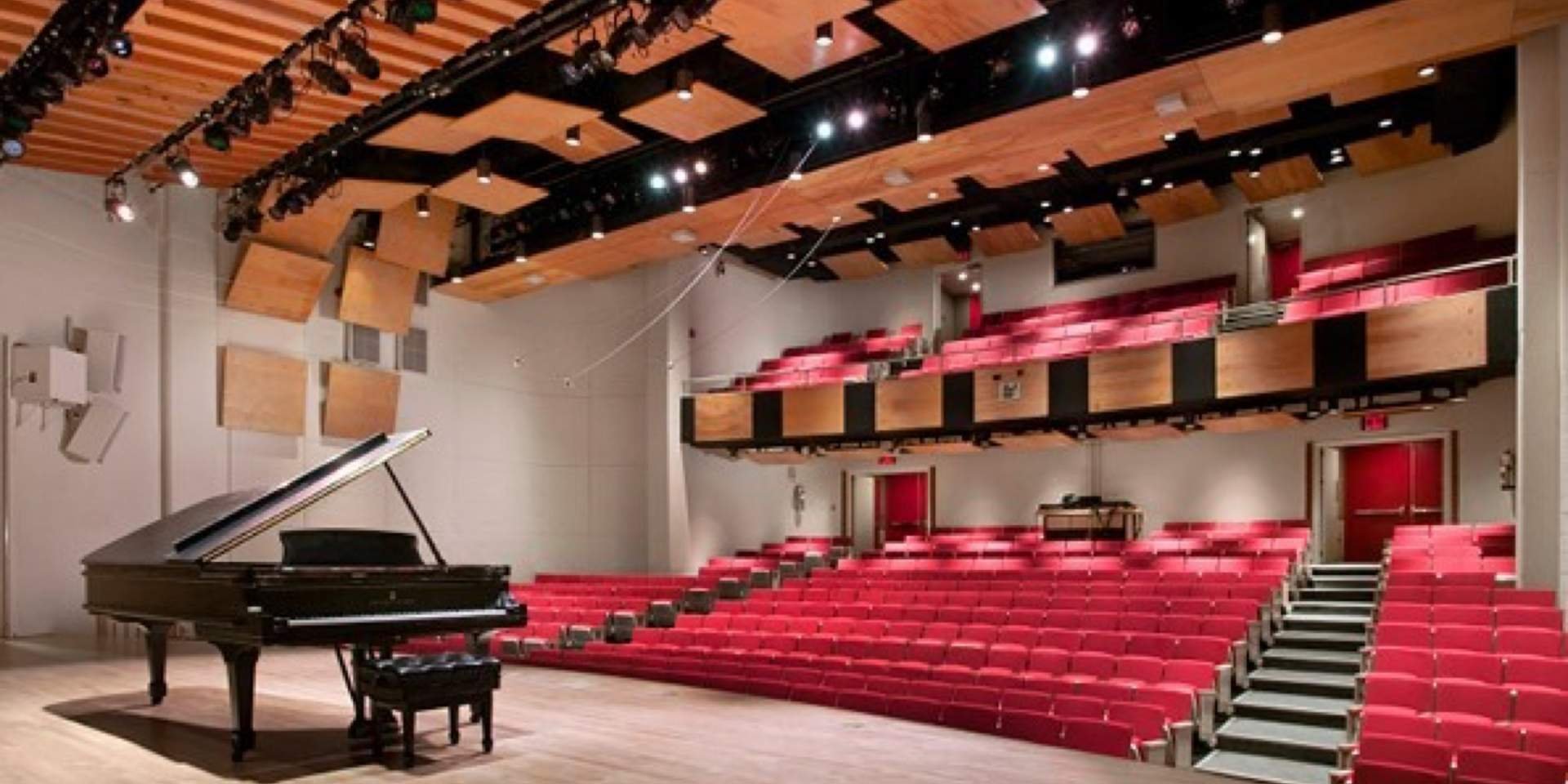Empty auditorium with a stage and grand piano in the center