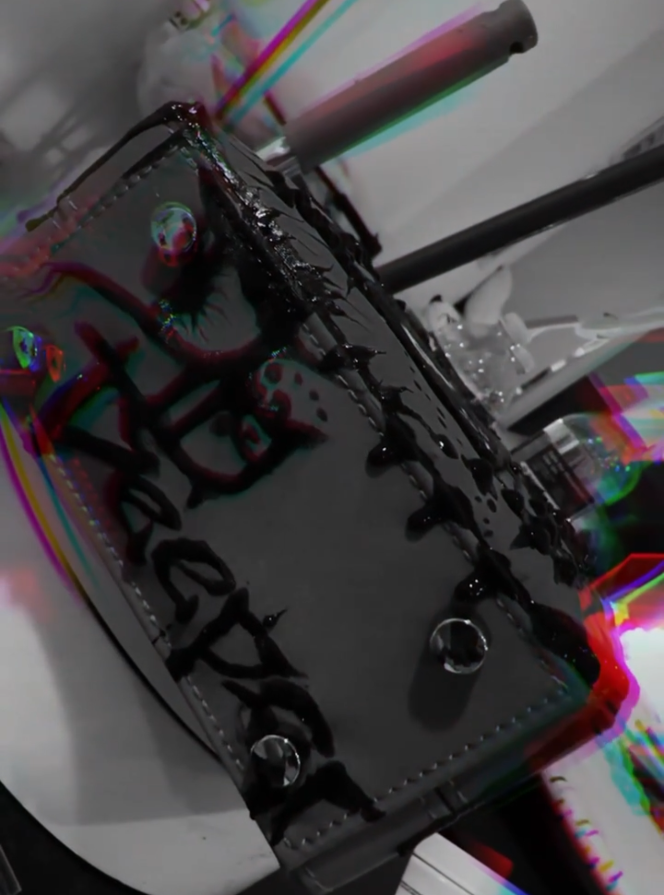 A black birthday cake with black icing, white writing that says 'Happy Birthday,' and colorful birthday candles on top.