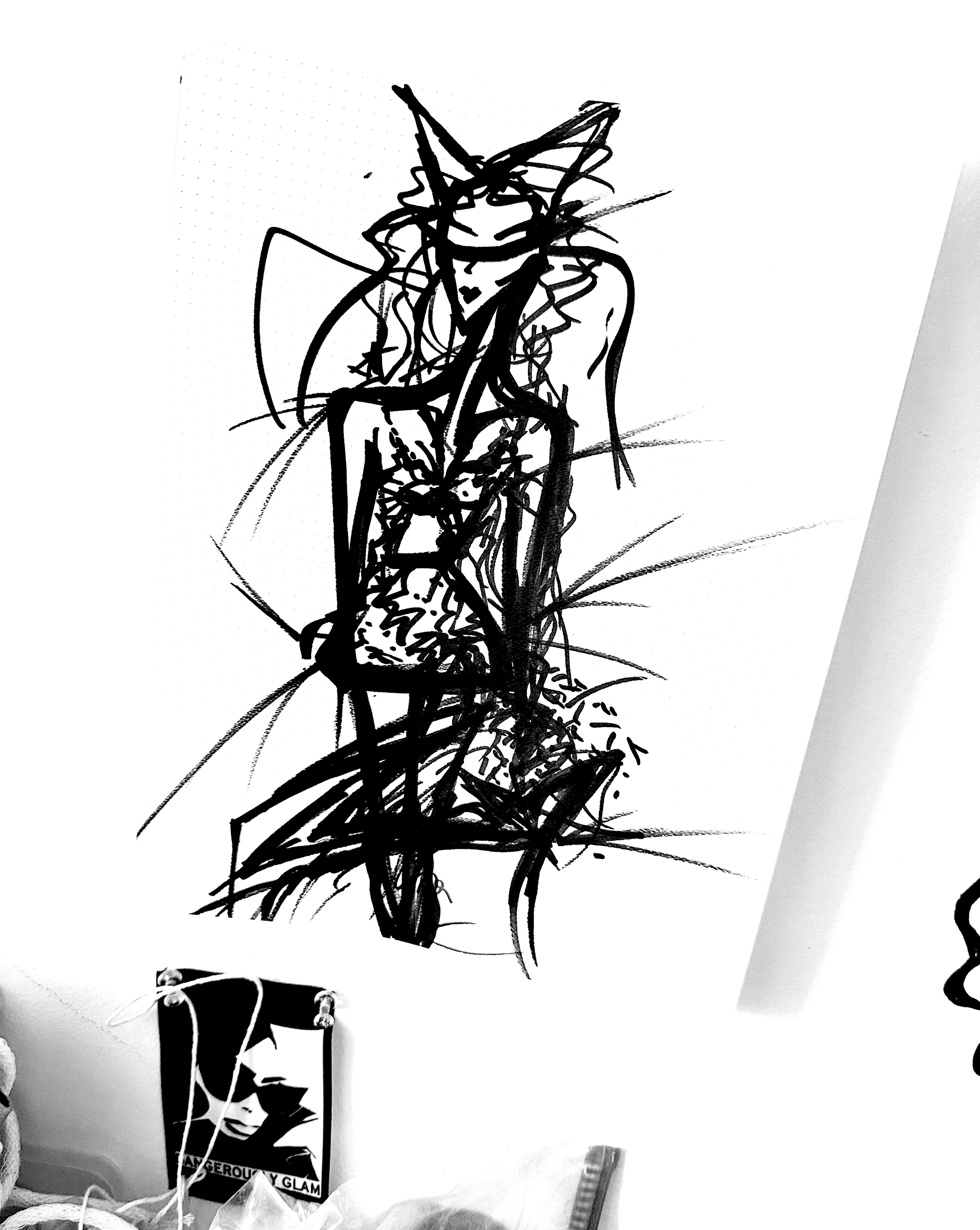 Black ink sketch of a woman with a large, pointed hat, sitting with her legs crossed, on a white paper background.