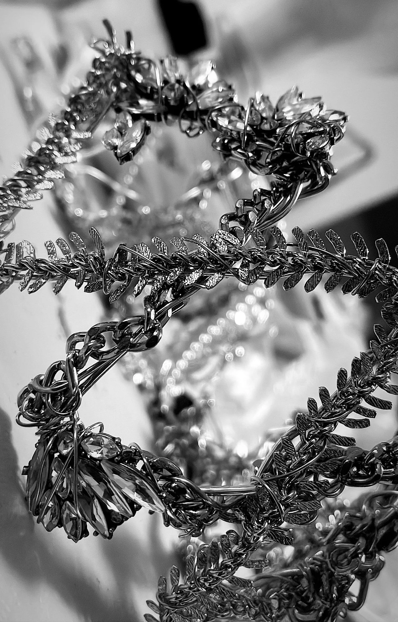 Close-up photo of tangled, shiny jewelry chains and accessories in black and white.