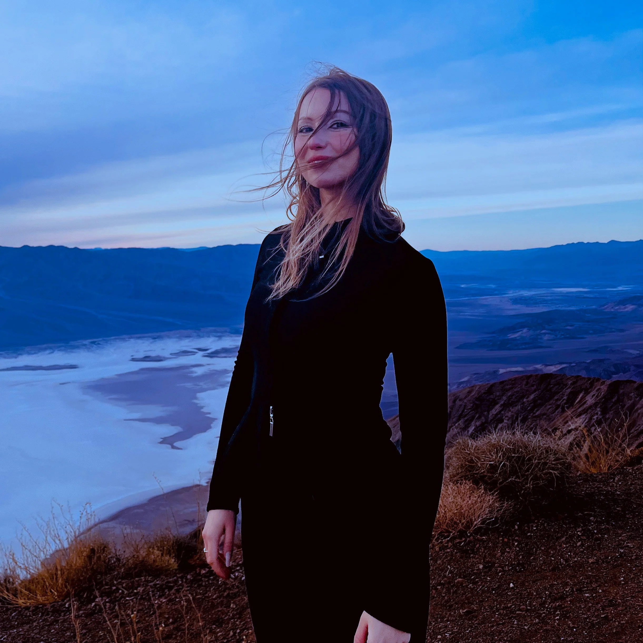 Beatrise Ziedina - TV/FILM/DOCUMENTARY Editor standing on a beach wearing black, hair blowing in the wind