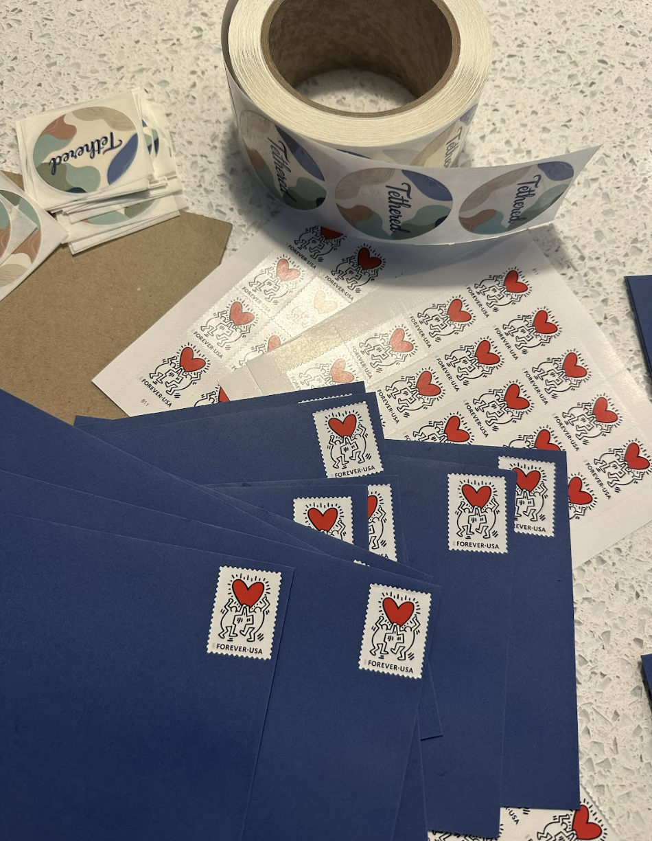 Stamps featuring a red heart and abstract design are scattered on a table.