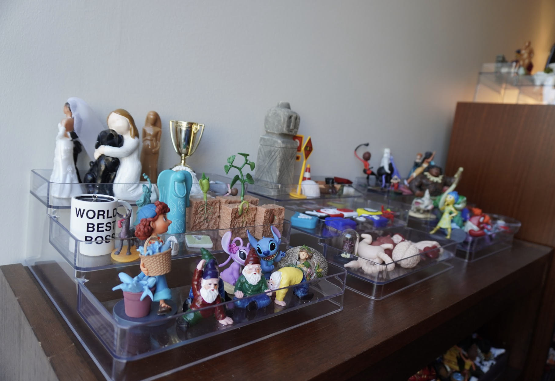 A desk with an organized display of small, colorful figurines, knick-knacks, and a cup labeled "World's Best Boss," creating a playful and quirky scene.