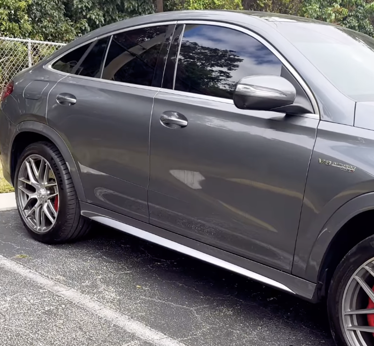 Gray luxury SUV parked on a street with tinted windows and custom alloy wheels.