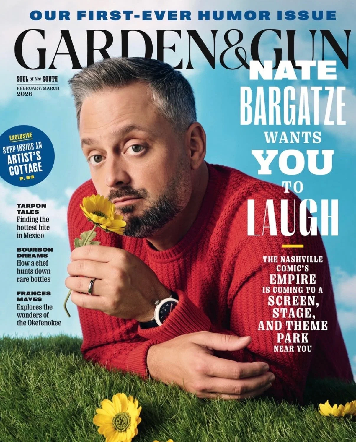 Cover of Garden & Gun magazine featuring Nate Bargatze in a red sweater smelling a yellow flower.