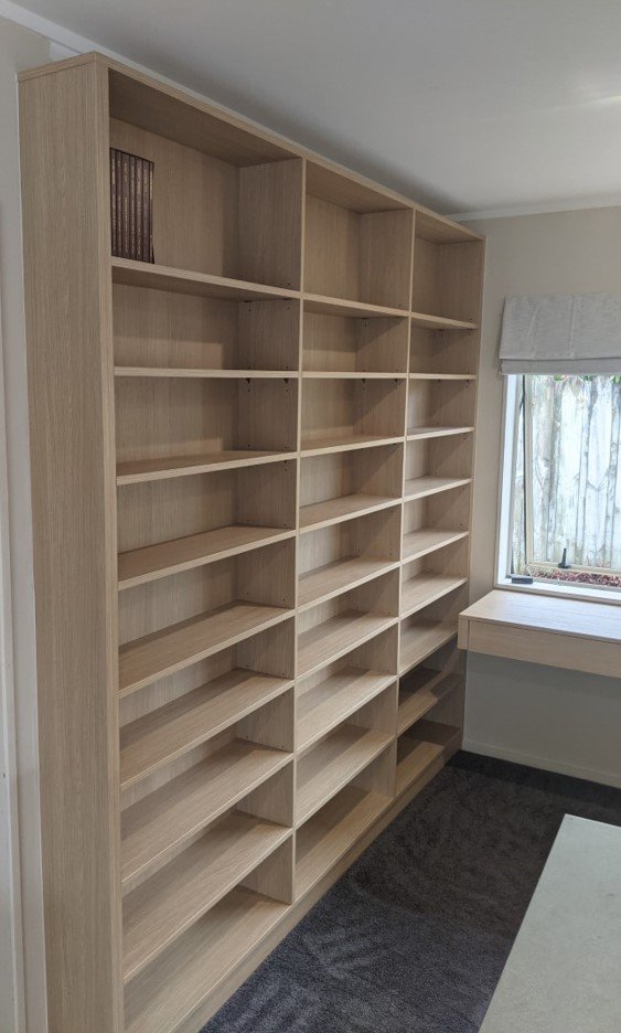 Empty wooden bookshelf unit next to a window in a room.
