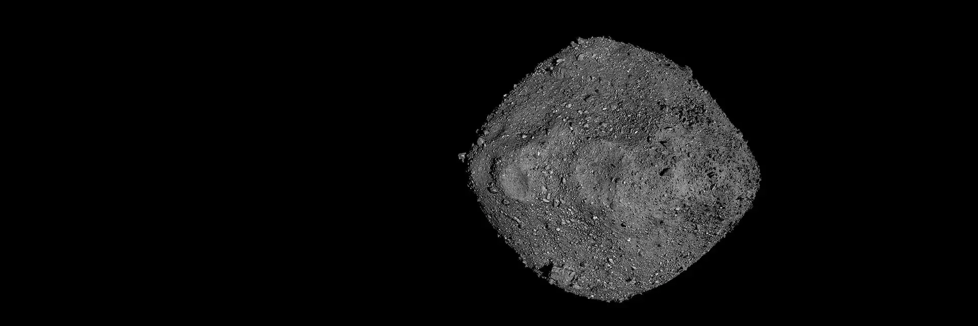 A gray asteroid with a rough, cratered surface floating in space against a black background.
