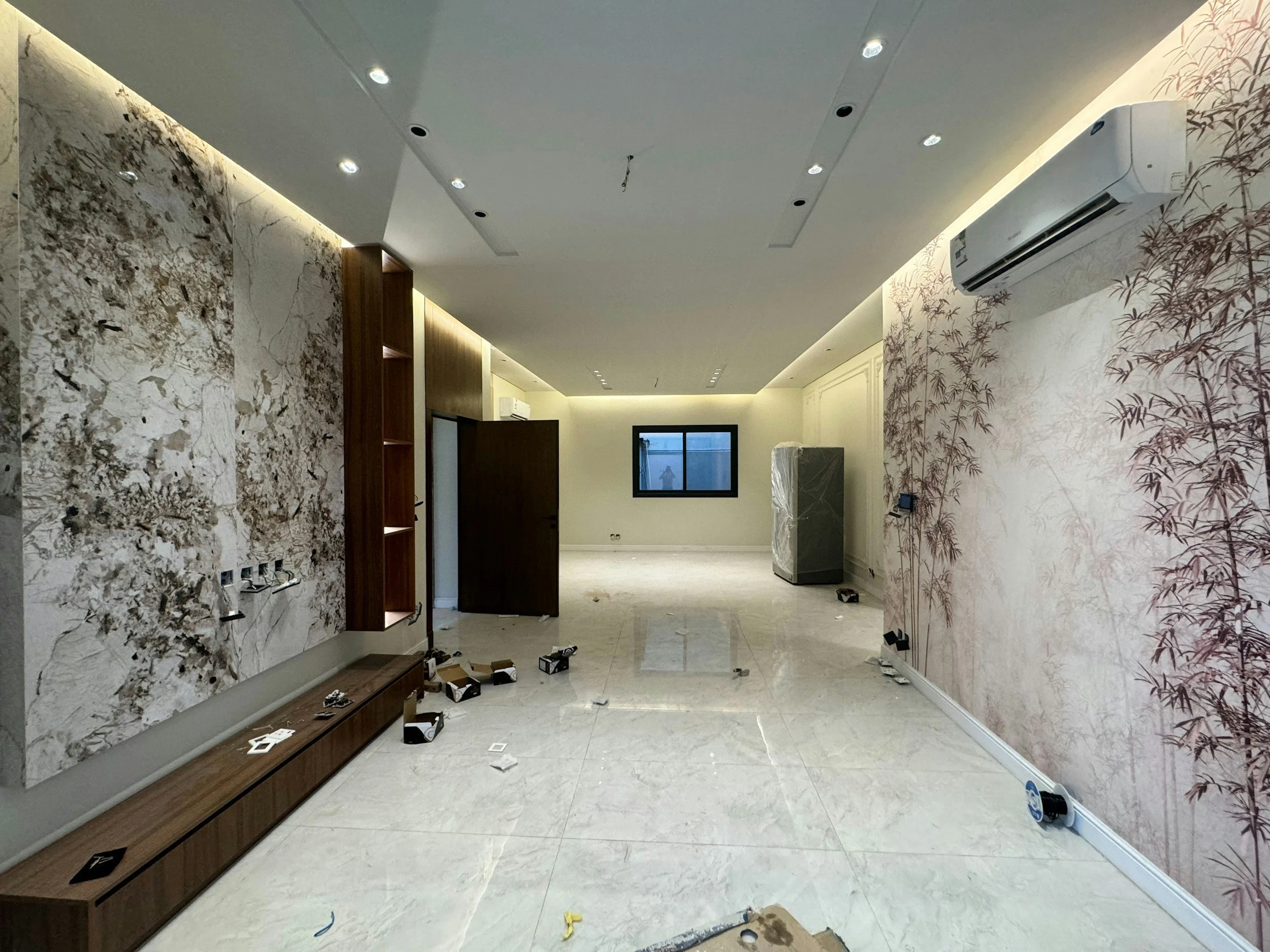 Interior room under renovation or installation, with unfinished walls, tools, and equipment scattered on the marble floor