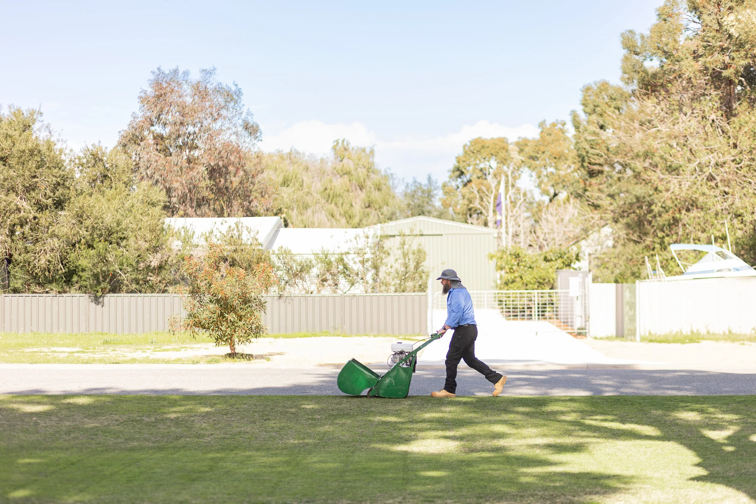 Professional lawn contractor using a cylinder mower mowing a medium sized high end residential house lawn.