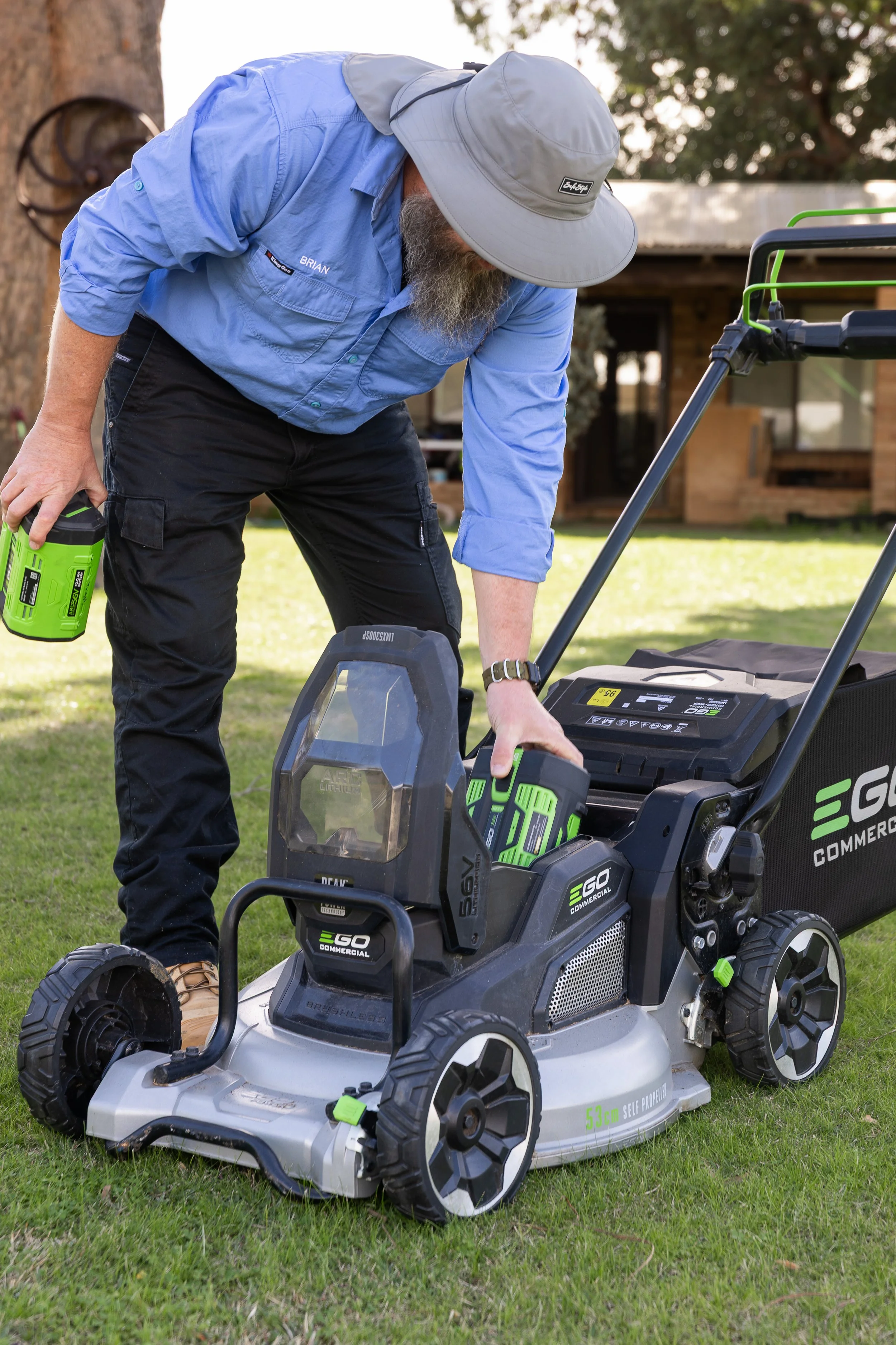 A professional lawn contractor putting a battery into a commercial electric lawn mower.